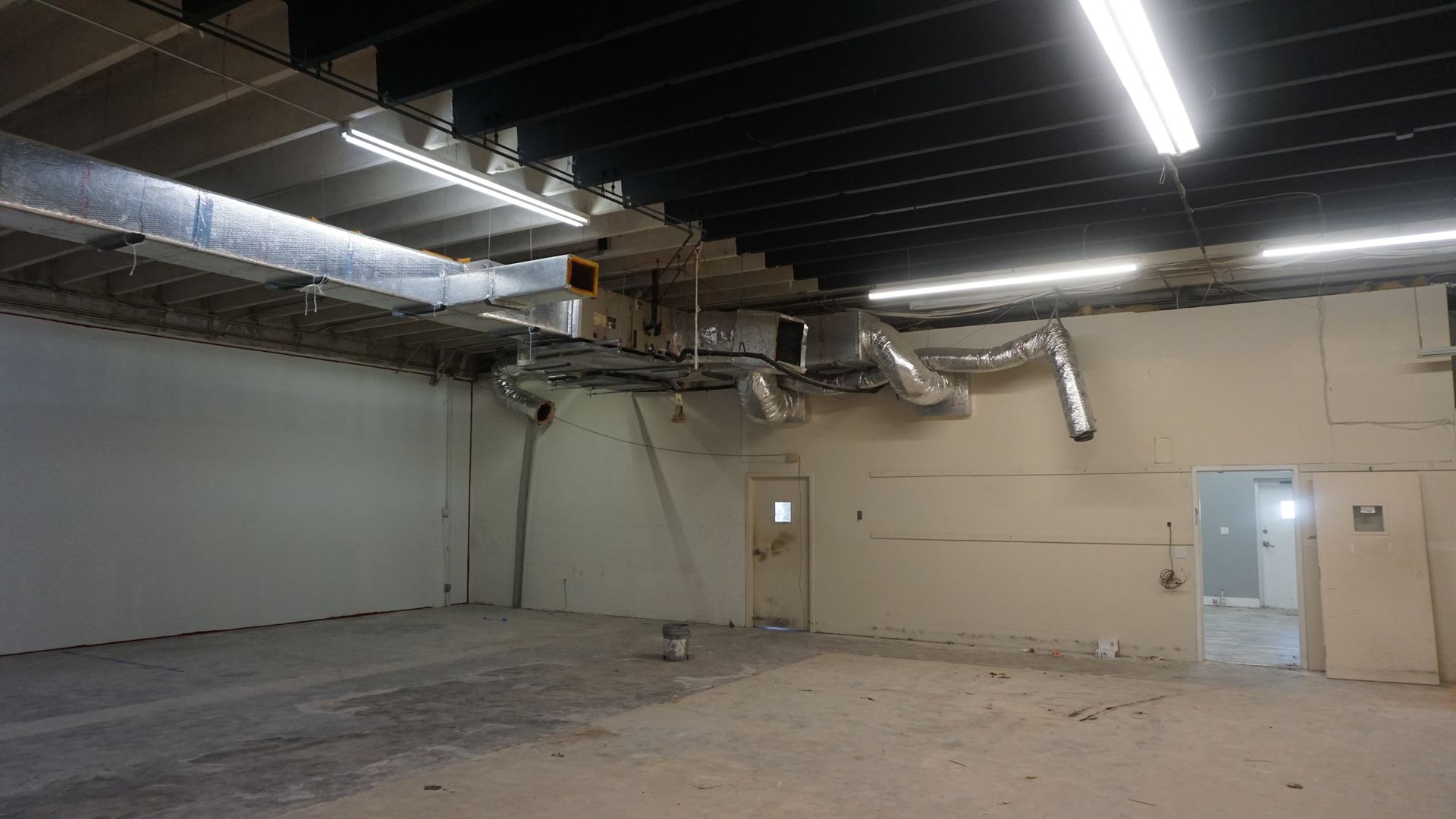 A large empty room with a ceiling fan and a door.