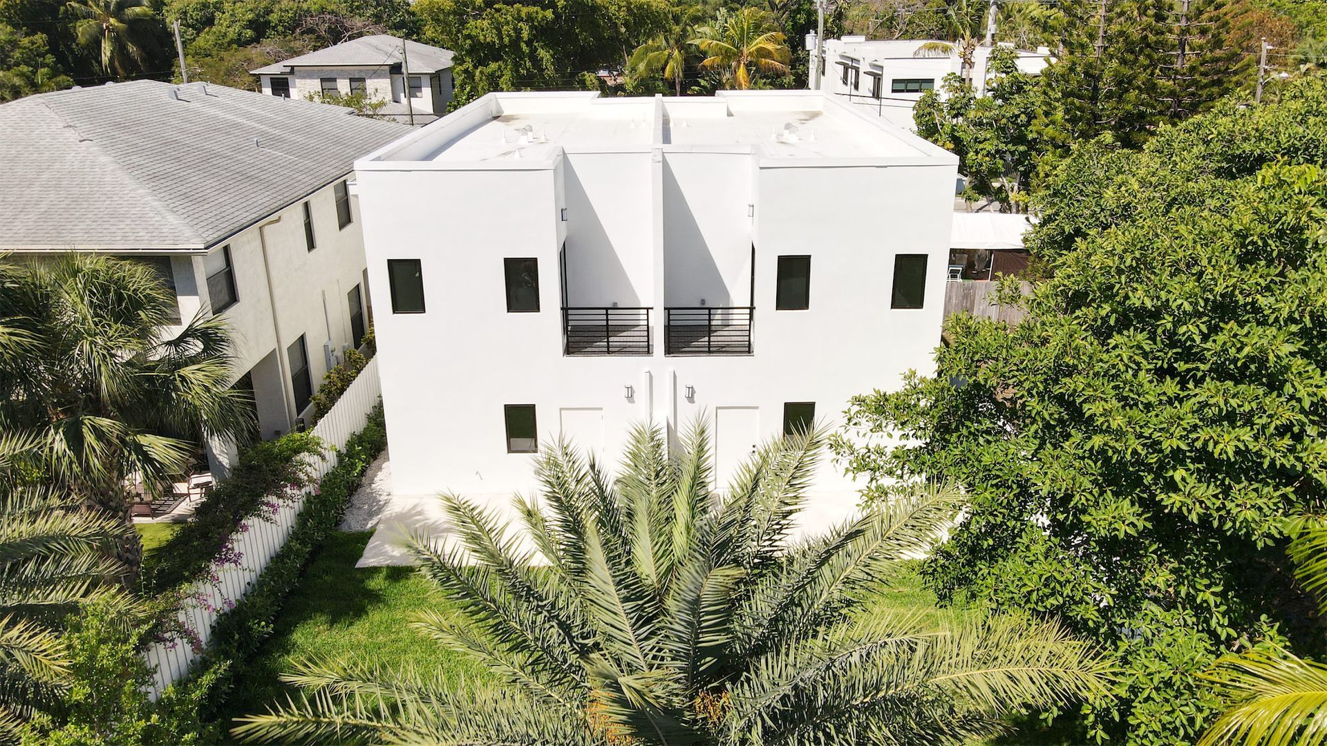 an aerial view of a white house surrounded by trees and bushes .