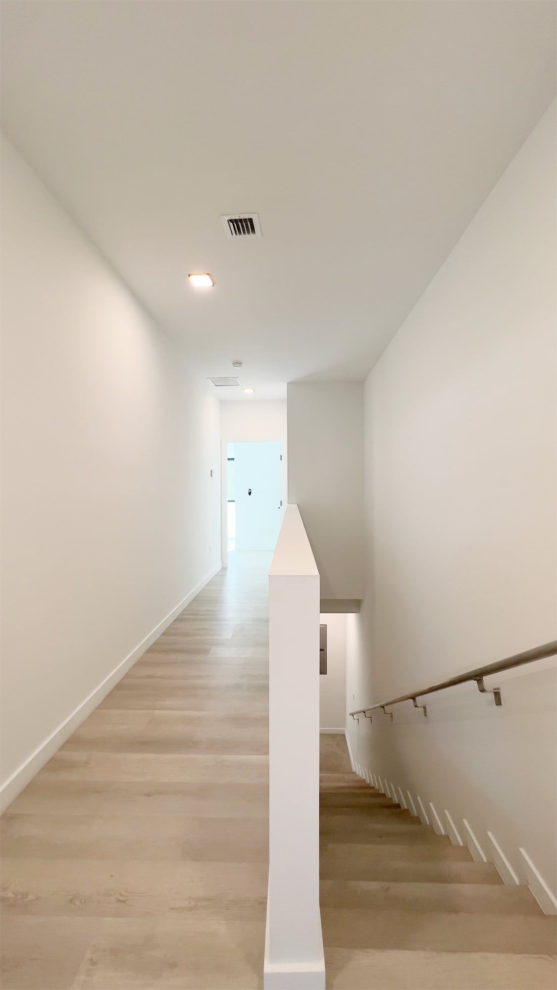 a long hallway with stairs leading up to the second floor of a house .