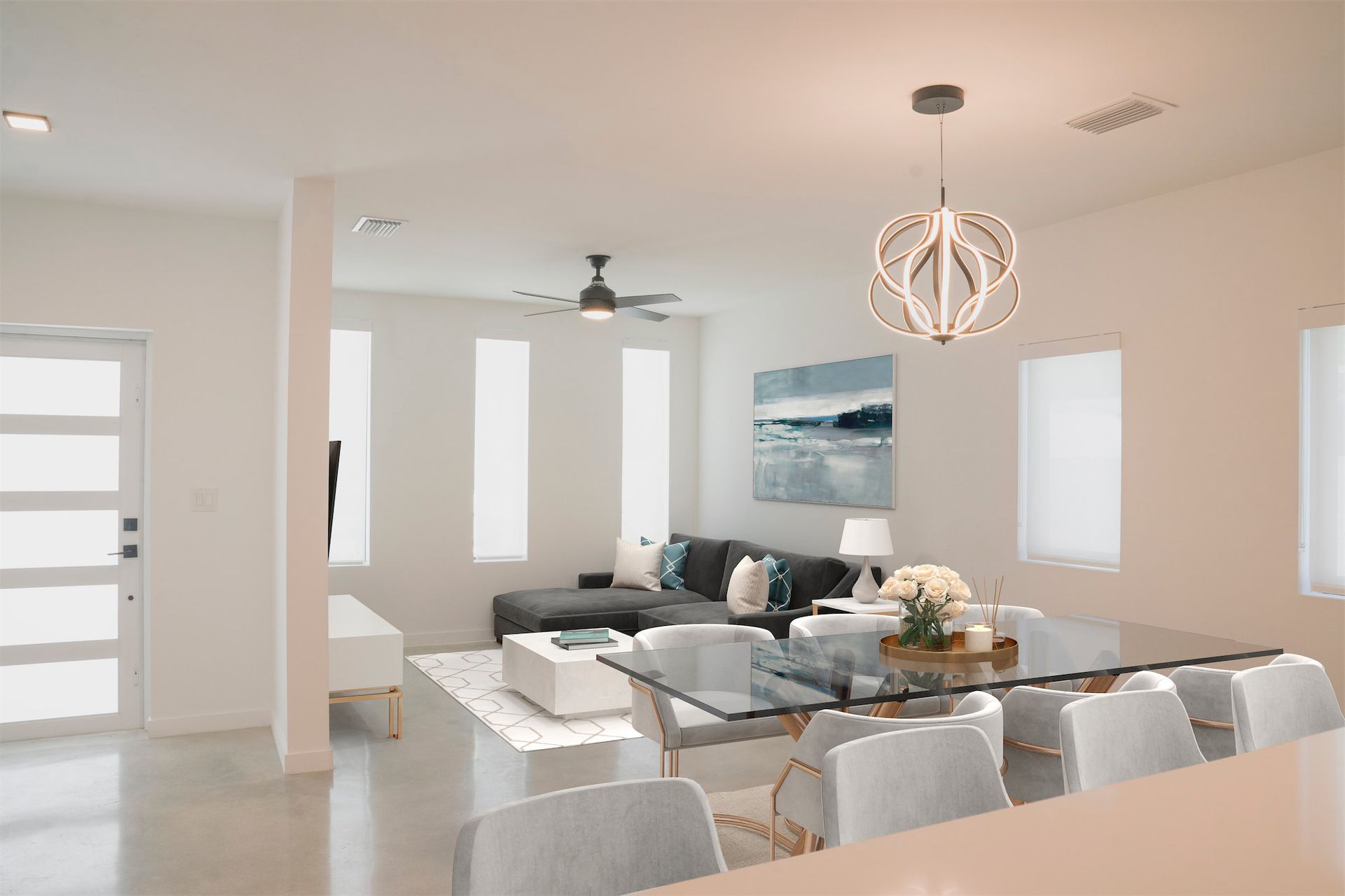 a living room with a glass table and chairs and a ceiling fan .