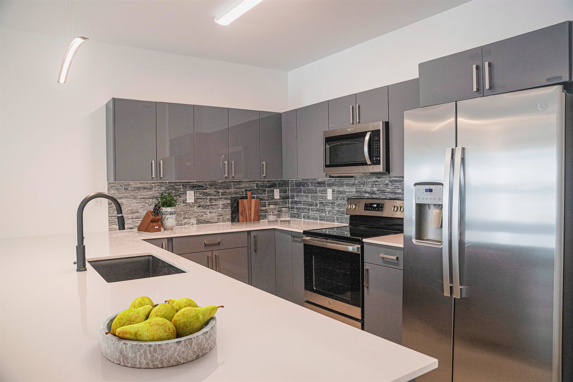 a kitchen with stainless steel appliances and a bowl of pears on the counter .