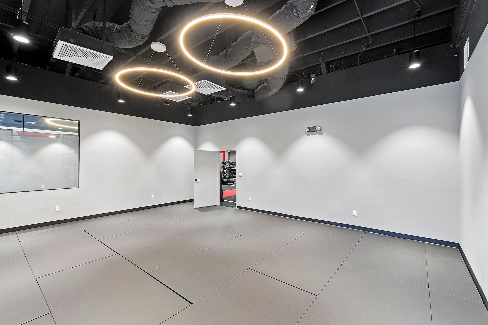 A large empty room with a karate mat on the floor.