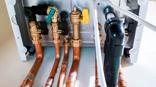 Person using a screwdriver to repair a white water heater.