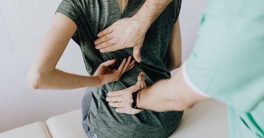 A man is examining a woman 's back while she sits on a table.