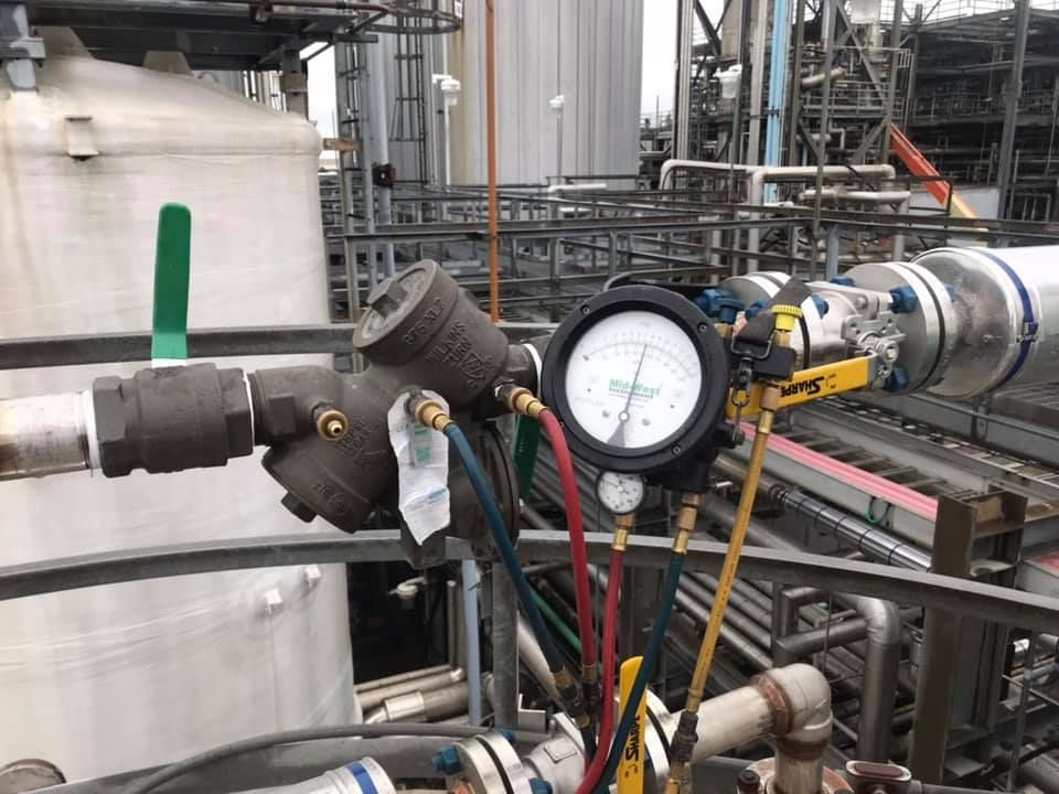 A manometer is sitting on top of a pipe in a factory.