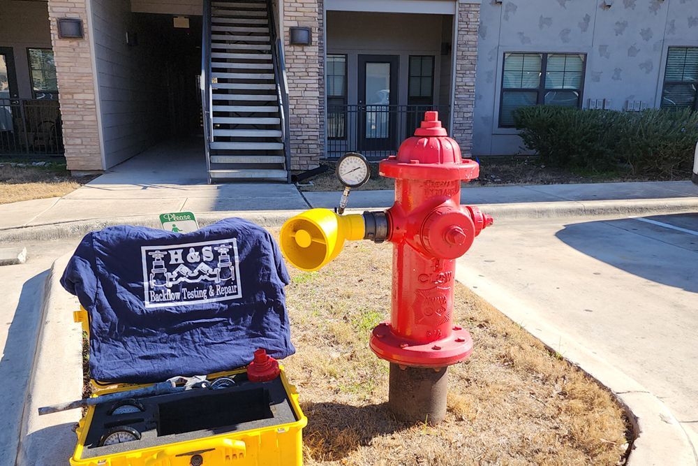 A man is working on a red fire hydrant in a parking lot.