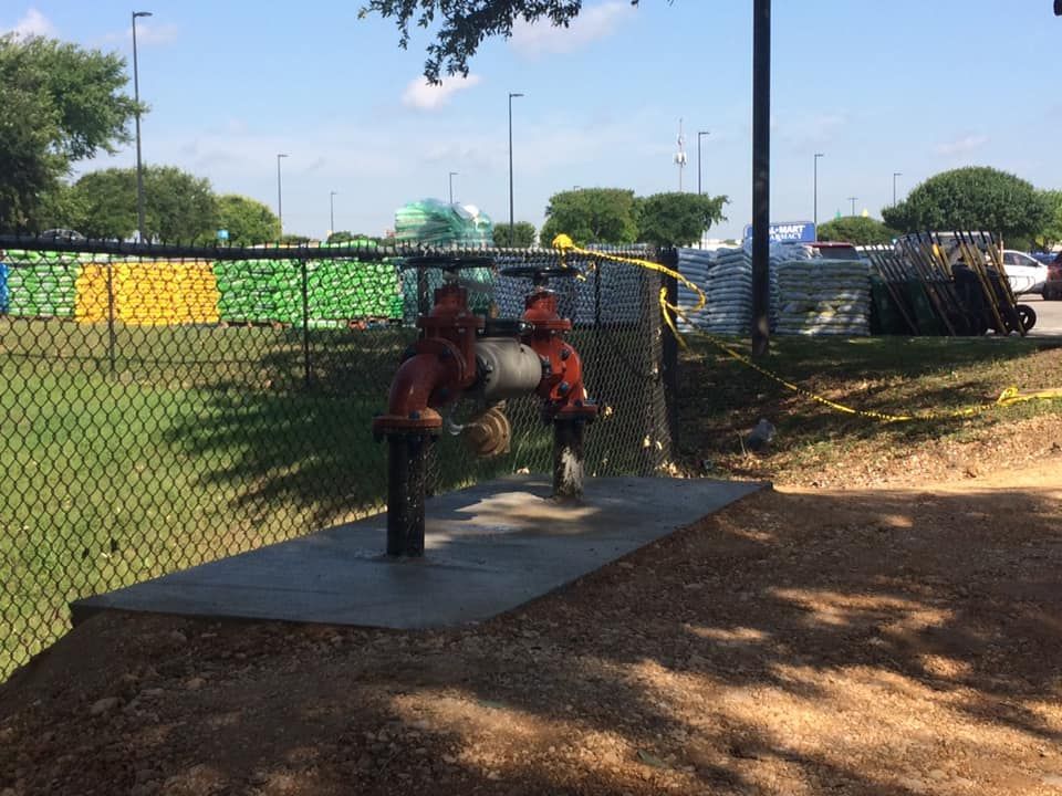 A fire hydrant is sitting in the dirt next to a chain link fence