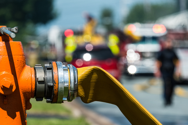 A fire hose is attached to an orange fire hydrant.