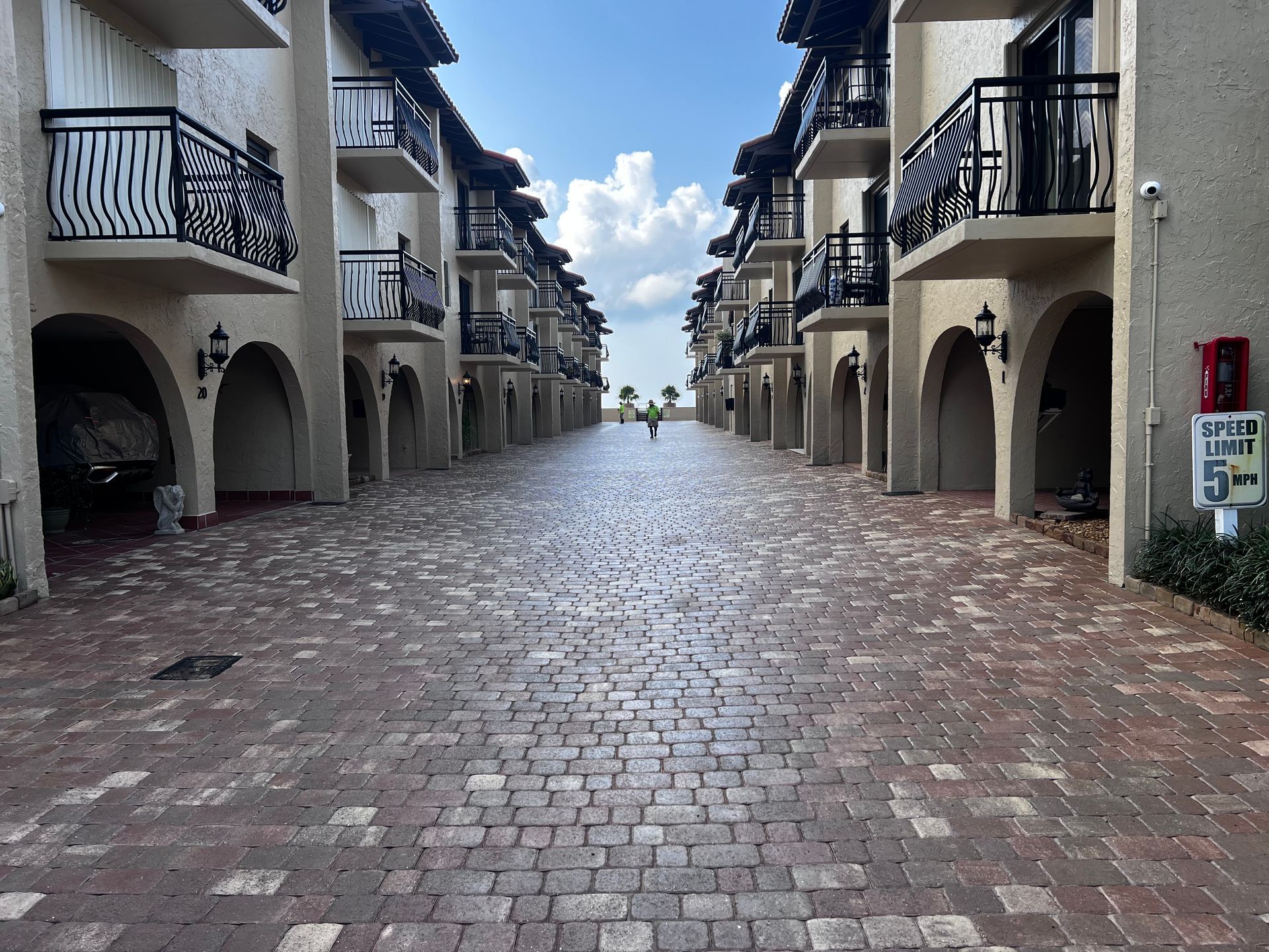 A brick walkway between two apartment buildings with balconies