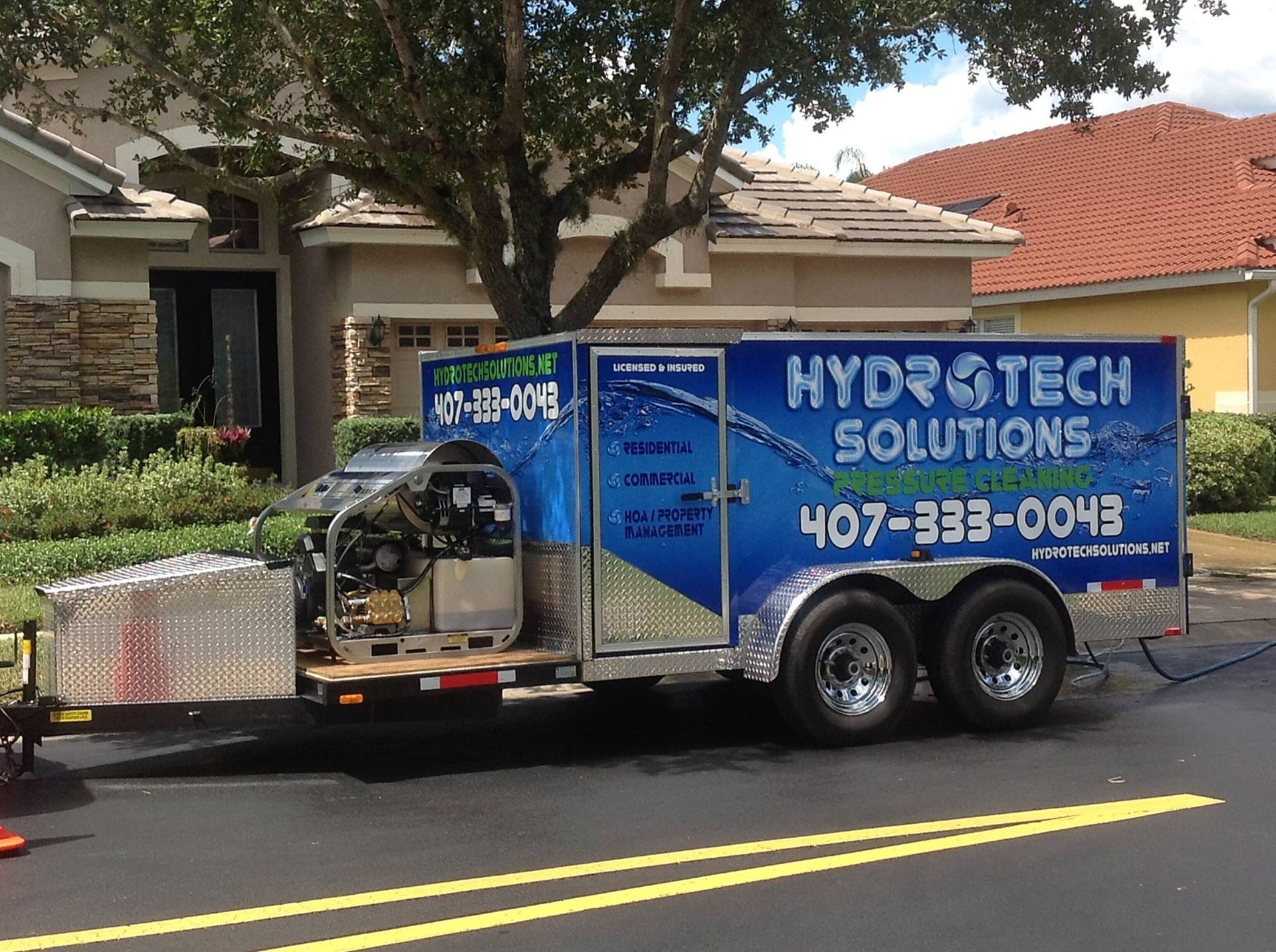 A hydrotech solutions trailer is parked in front of a house