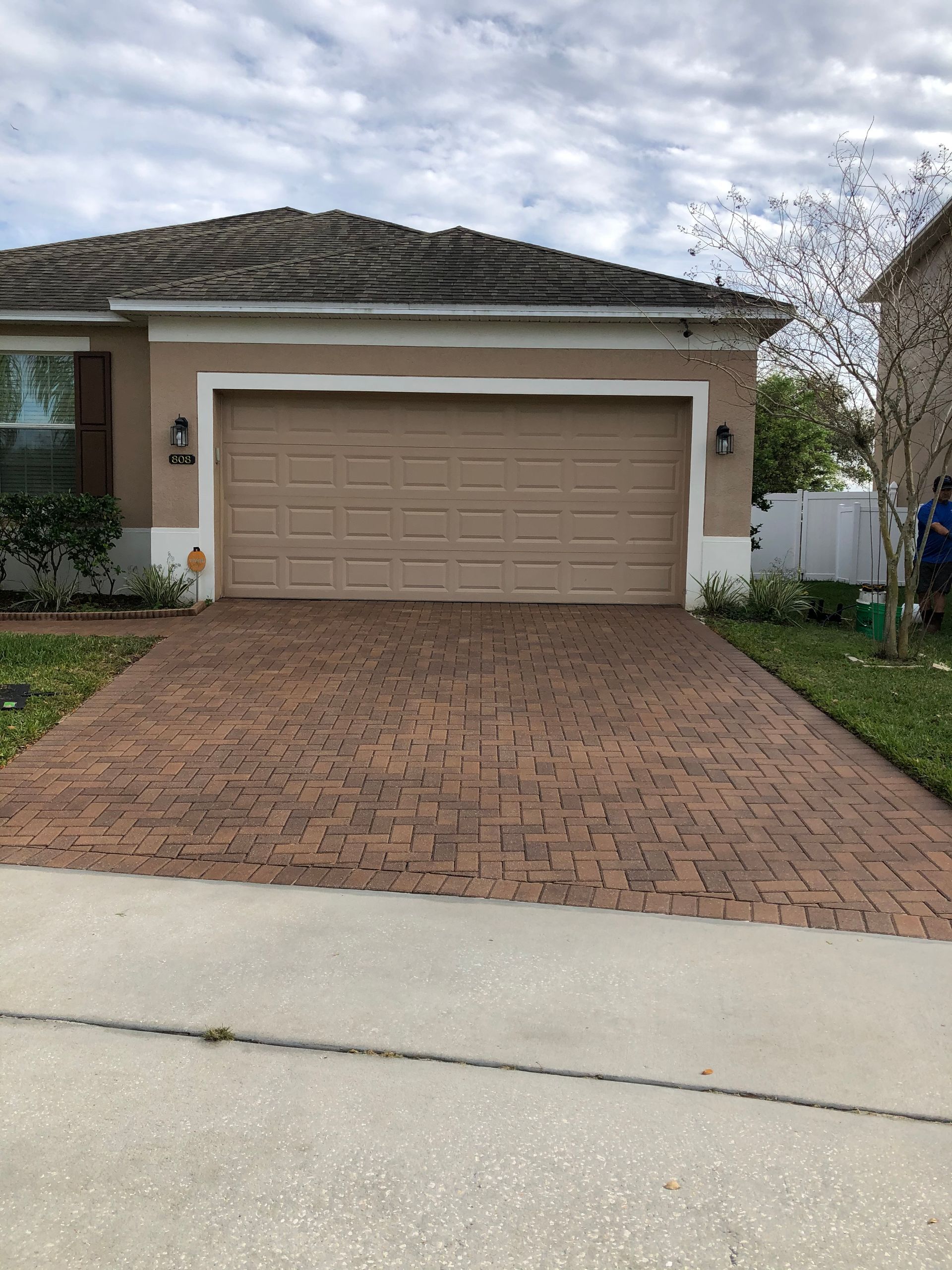 A house with a tan garage door and a brick driveway