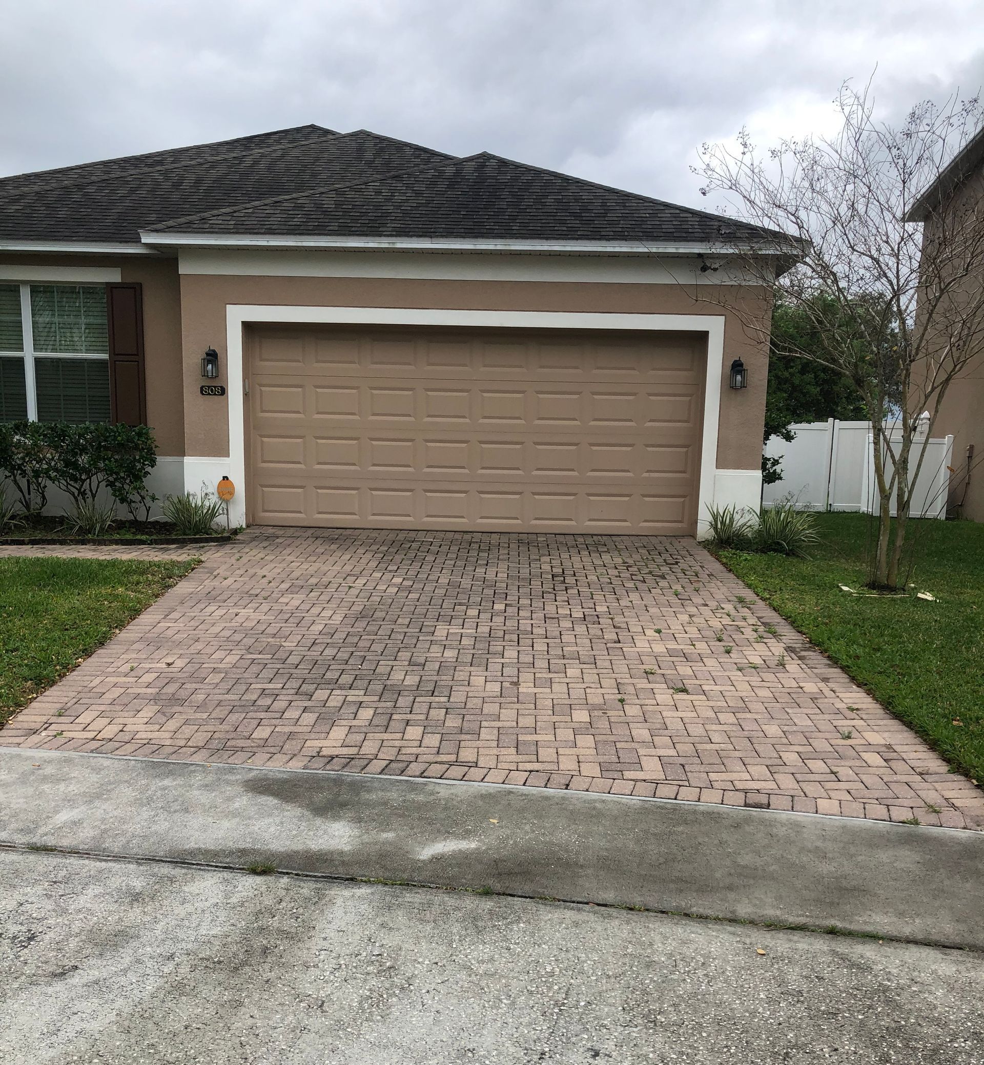 A house with a garage door and a brick driveway