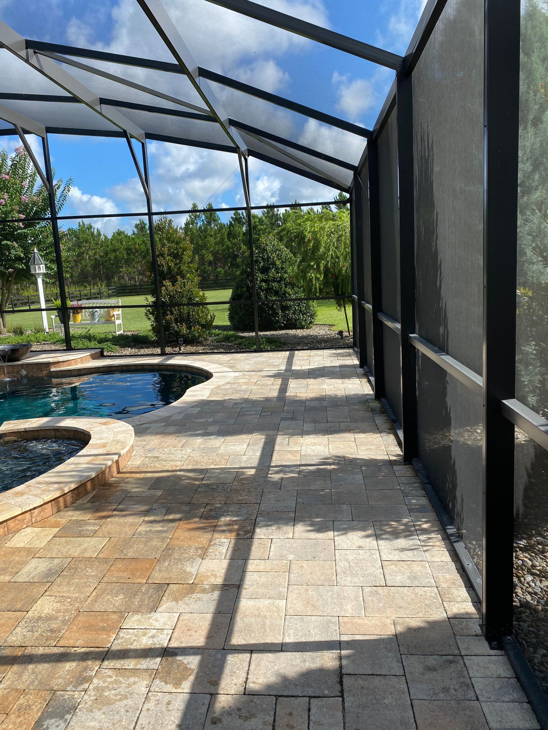 A screened in patio with a swimming pool in the background.