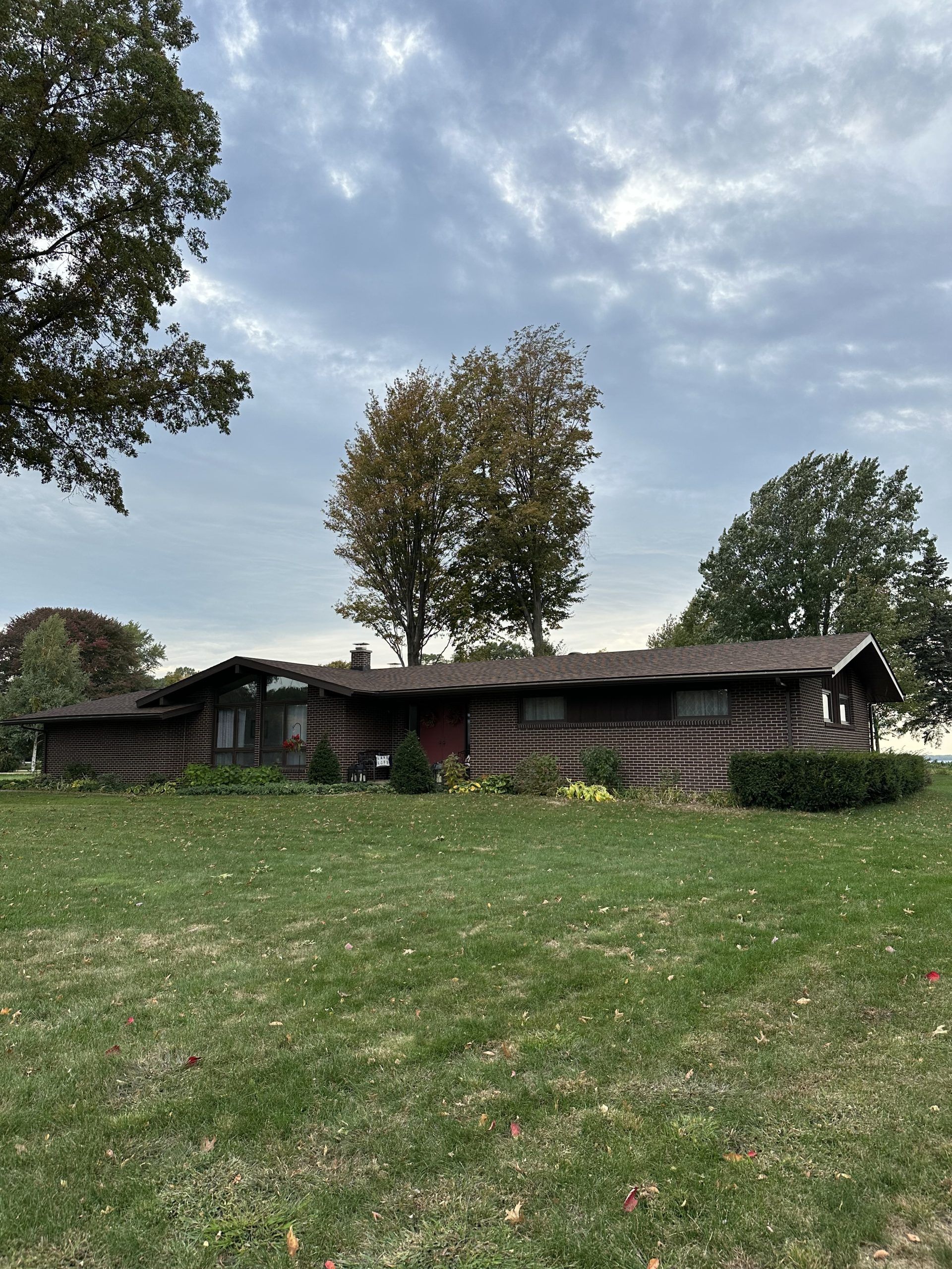 Log cabin style house with a green lawn under a cloudy sky.