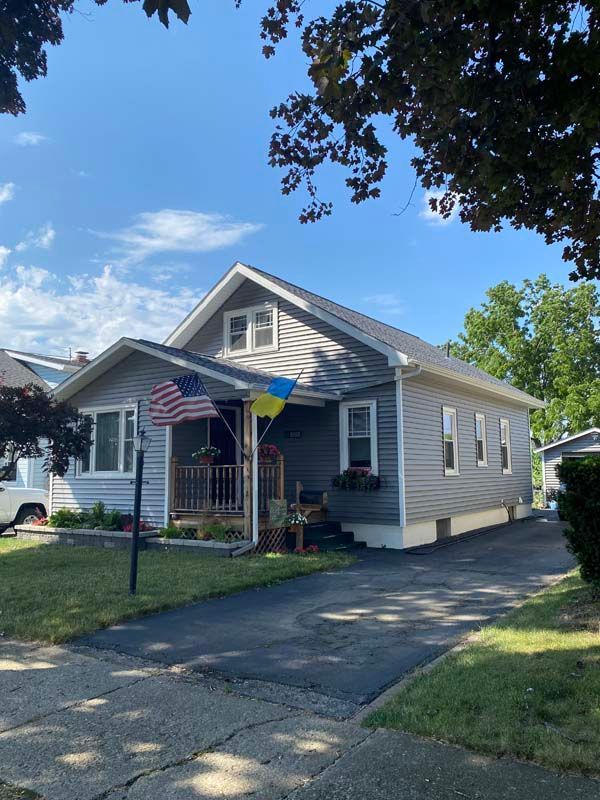 House with blue siding, American and Ukrainian flags on porch, driveway.