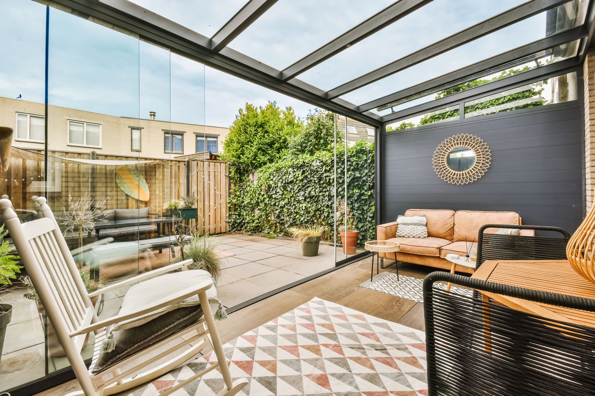 A patio with a rocking chair , couch , table and rug.