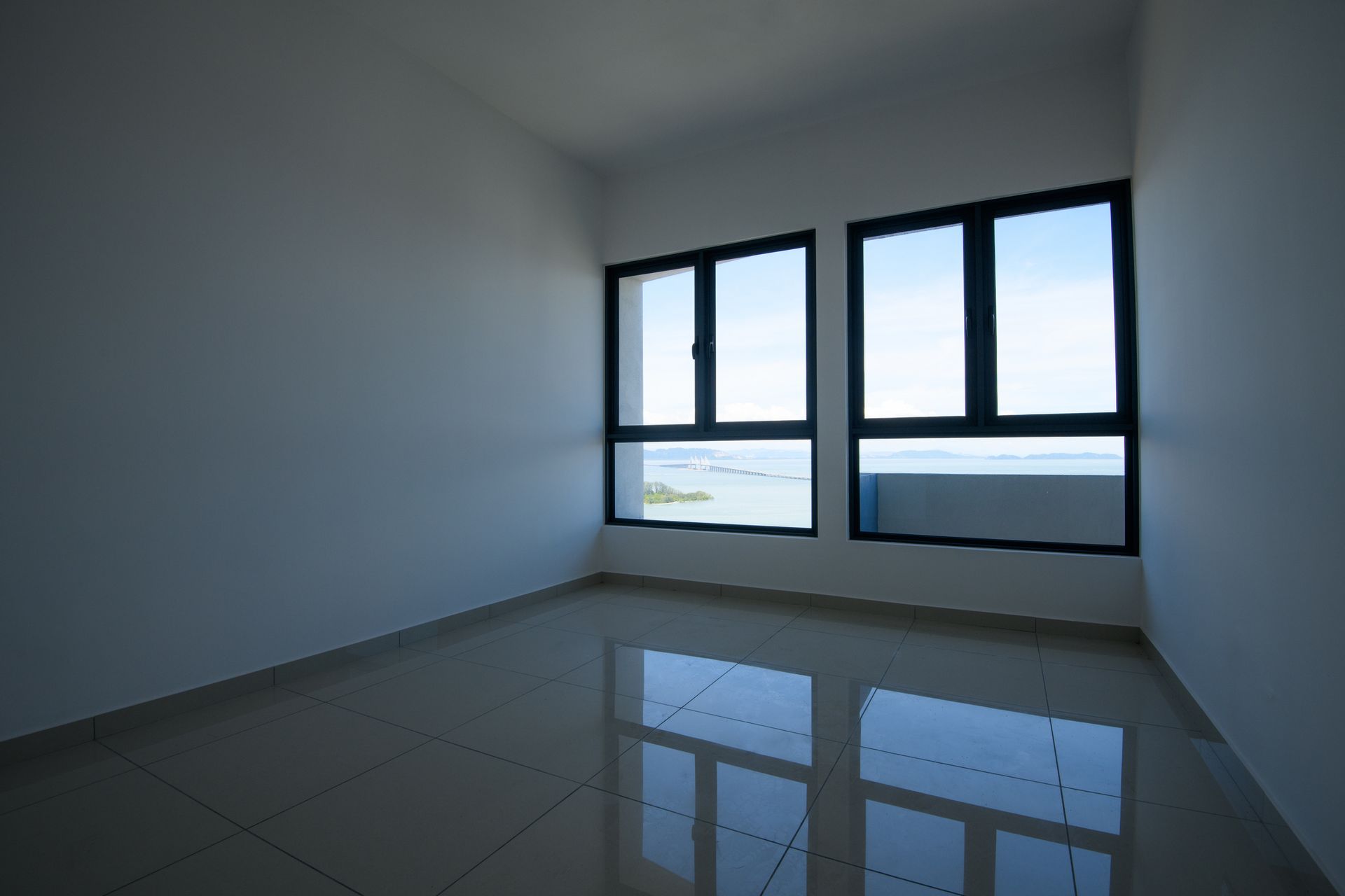 An empty room with two windows and a tiled floor