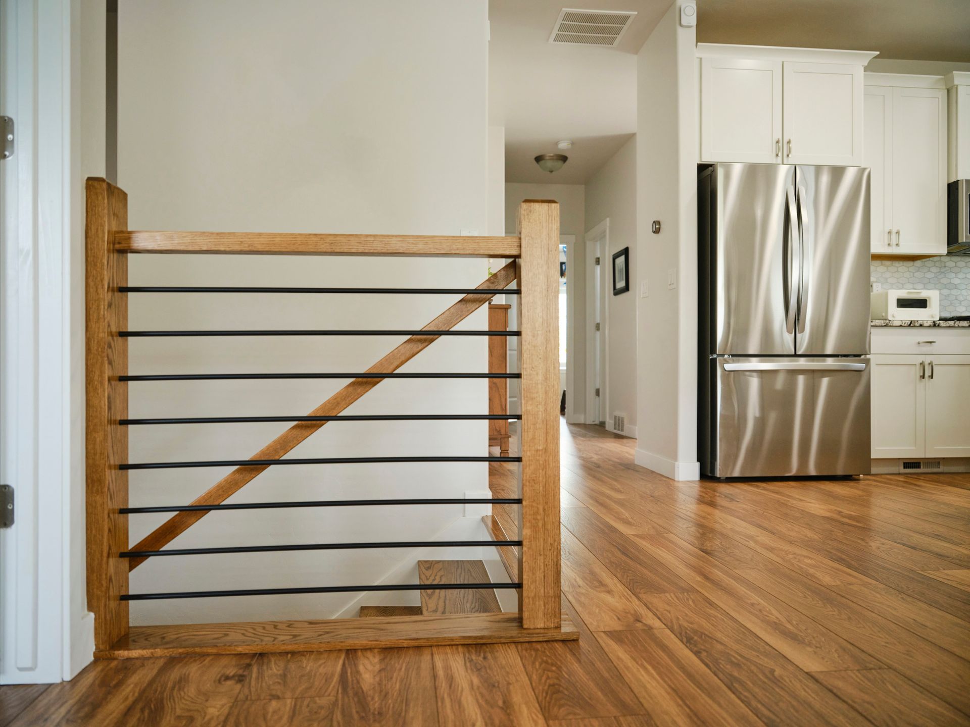 A kitchen with a stainless steel refrigerator and a wooden staircase A kitchen with a stainless steel refrigerator and a wooden staircase