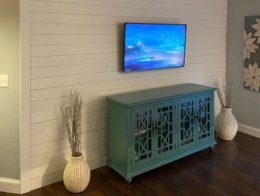 A living room with a blue dresser and a flat screen tv mounted to the wall. A living room with a blue dresser and a flat screen tv mounted to the wall.