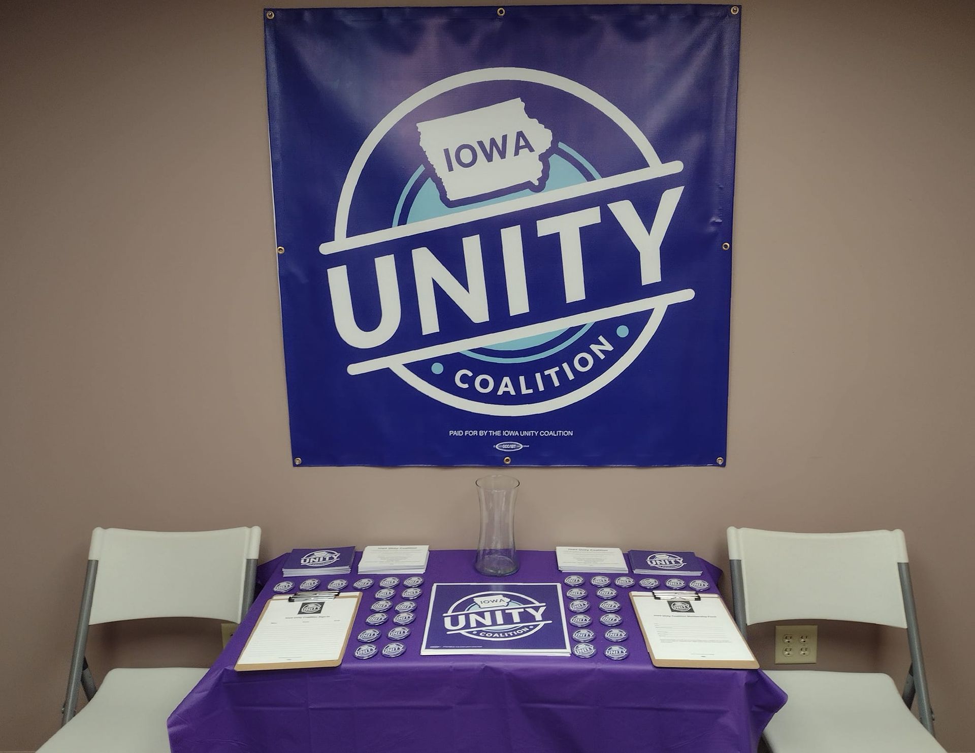 a table with sign-in and buttons, stickers, and forms for Iowa Unity Coalition