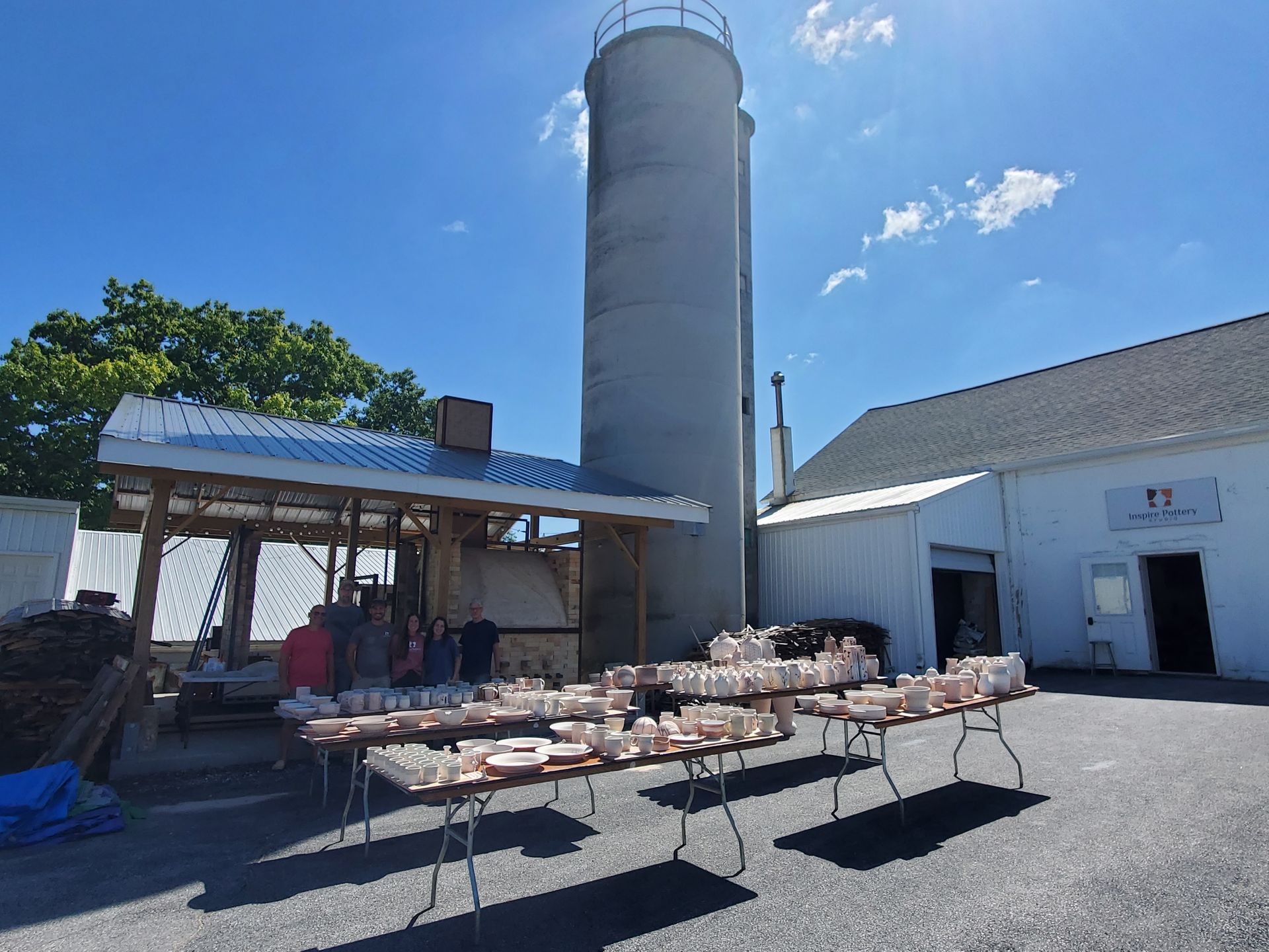 A group of tables are lined up in front of a building with a silo in the background.