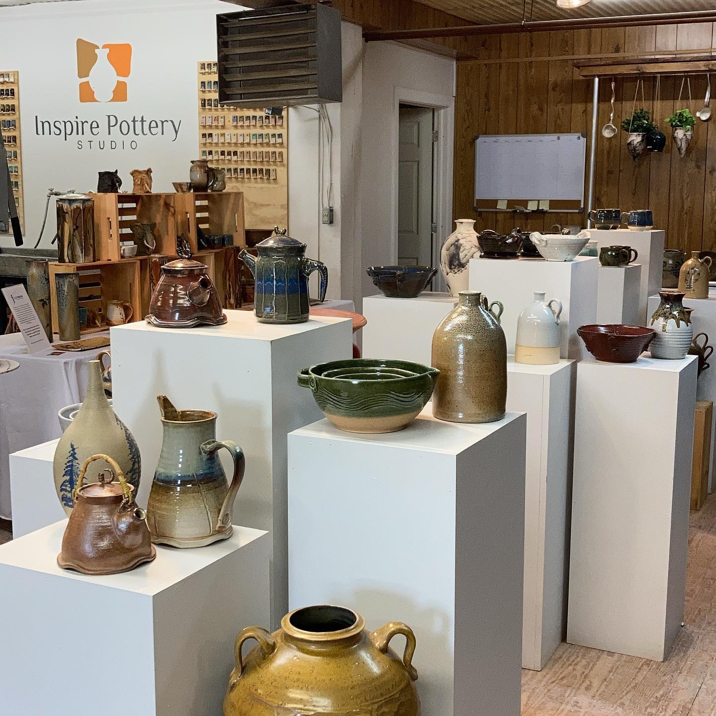 A room filled with lots of vases and a sign that says inspire pottery