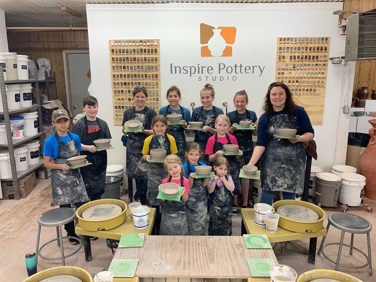 A group of children are posing for a picture in a pottery studio.