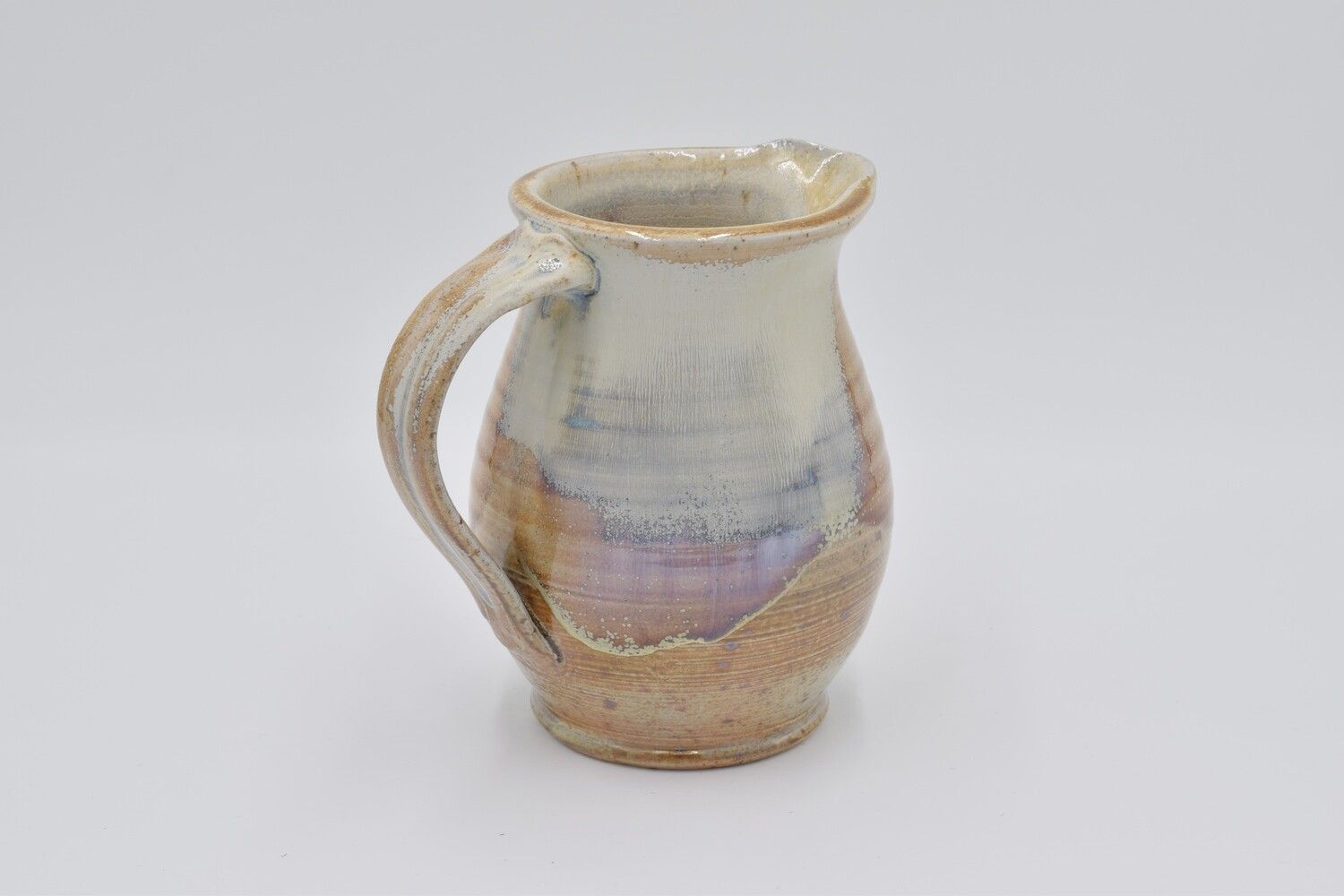 A small ceramic mug with a handle is sitting on a white surface.