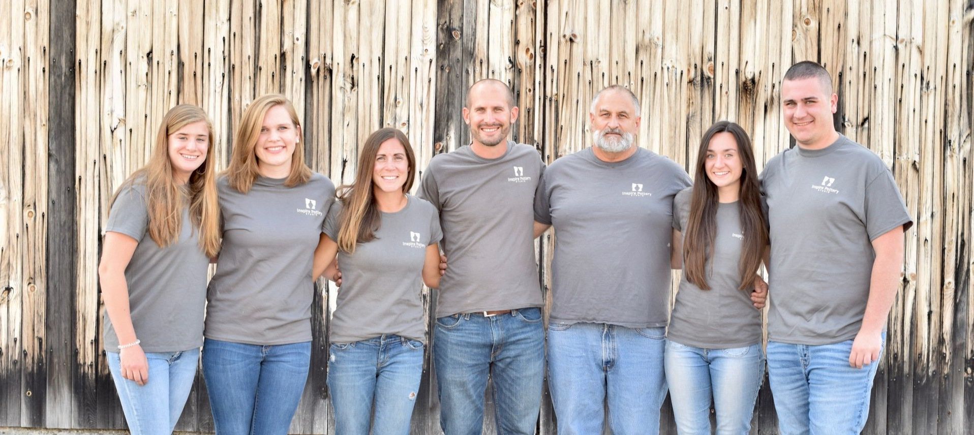 A group of people are posing for a picture in front of a wooden wall.