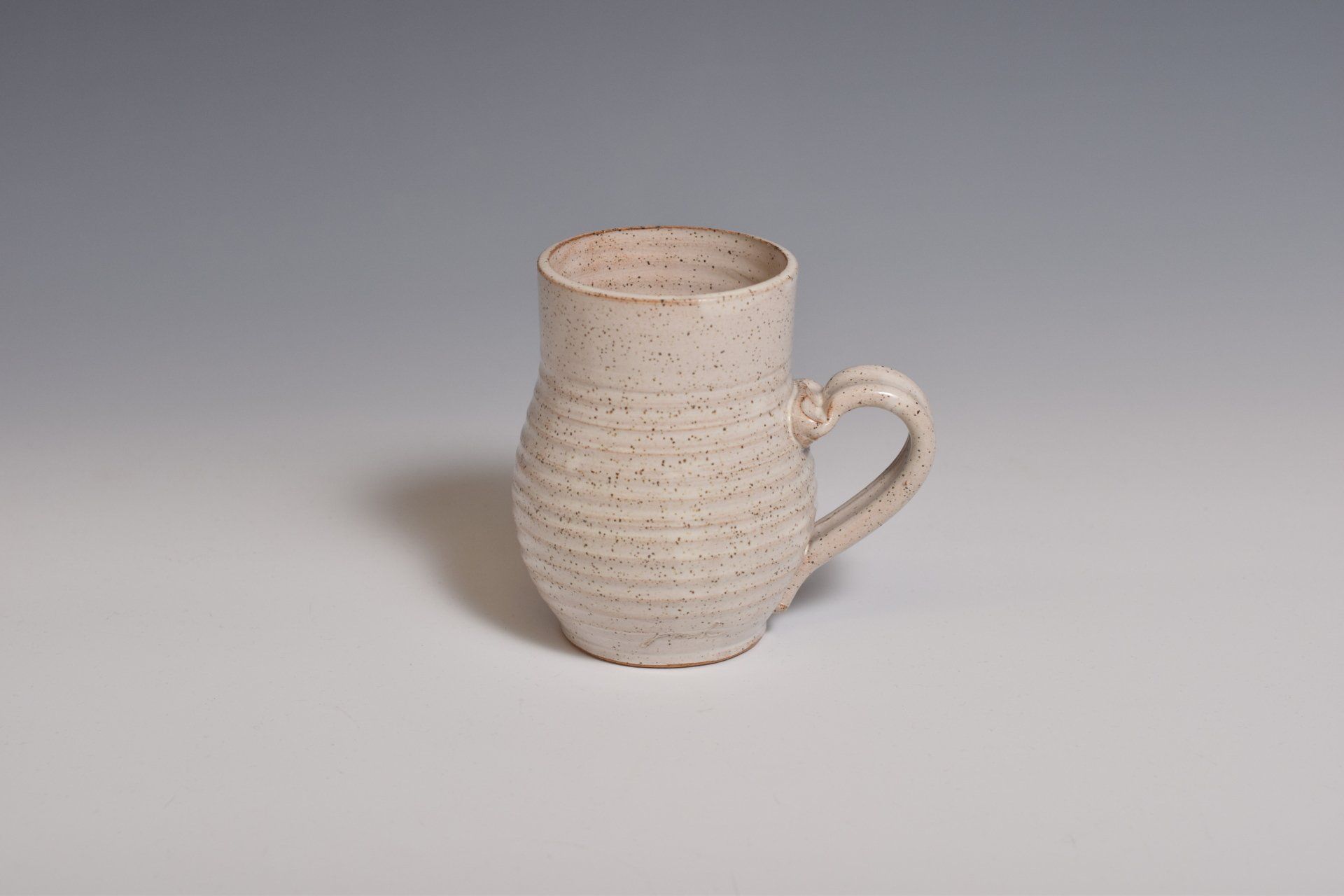 a white mug with a handle is sitting on a table .
