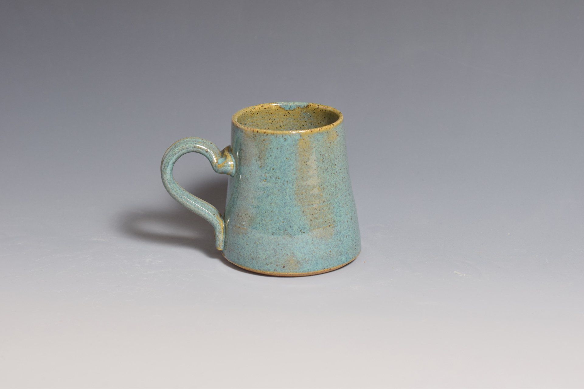 a small blue mug with a handle is sitting on a table .