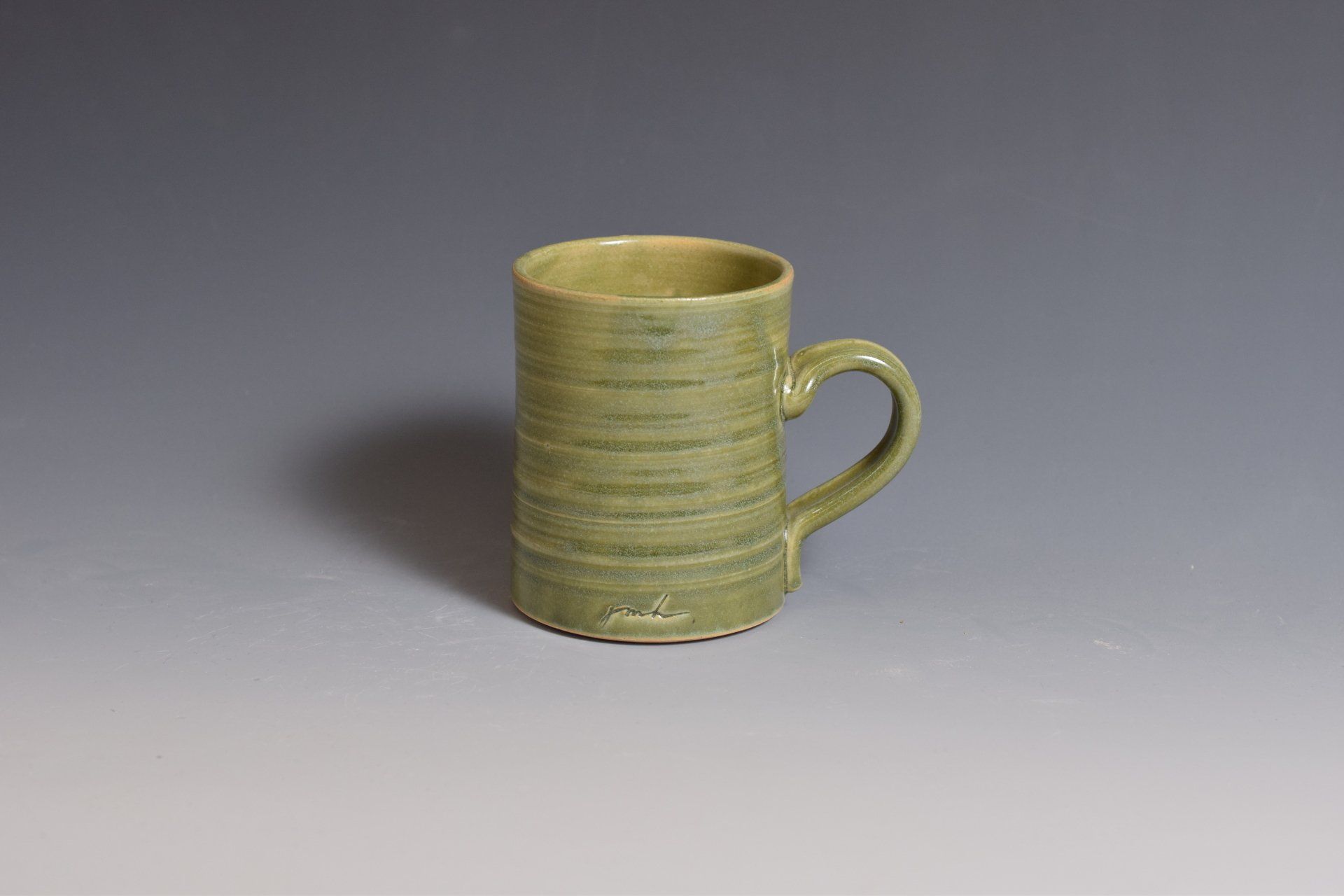 a green mug with a handle is sitting on a table .