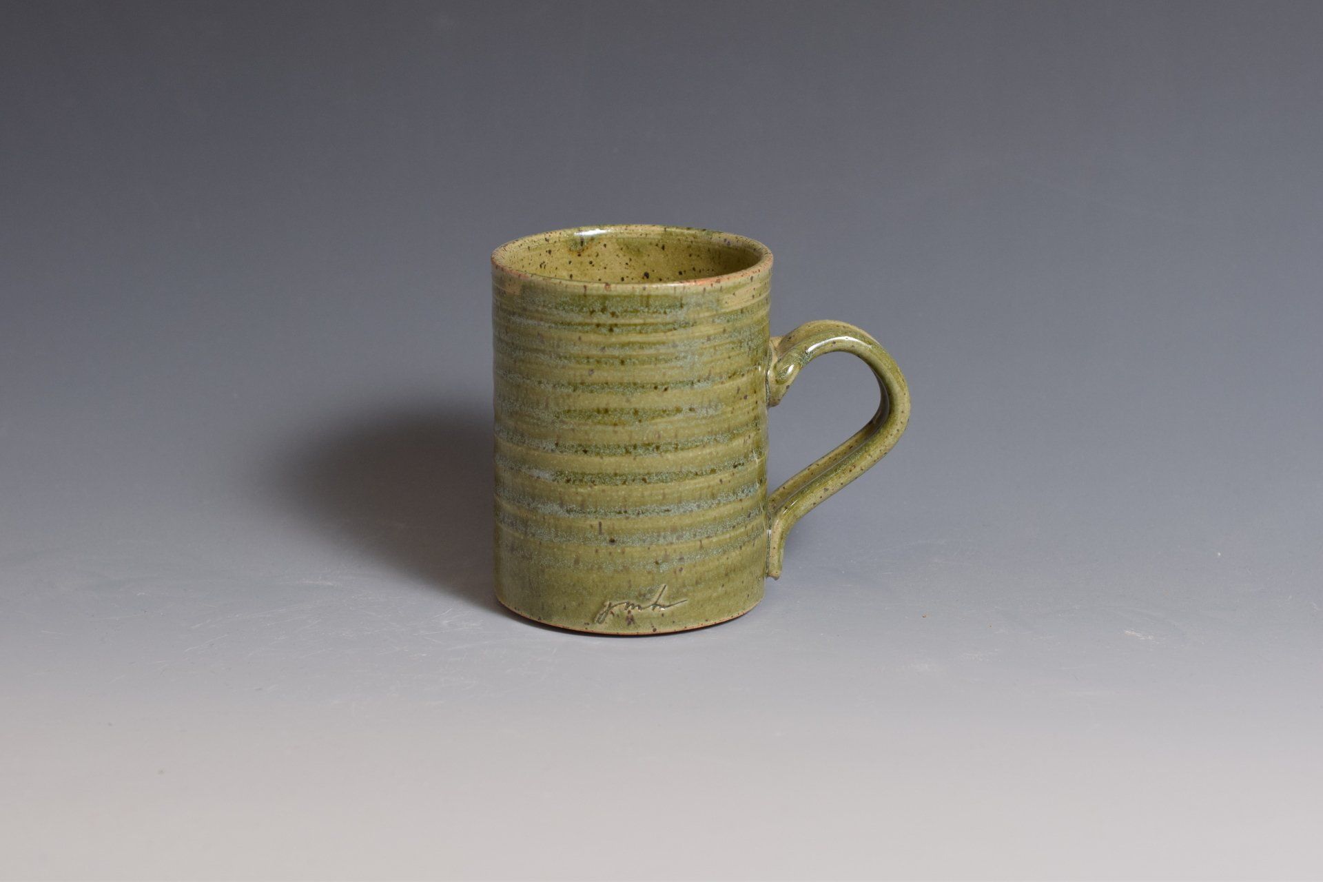 a green mug with a handle is sitting on a table .