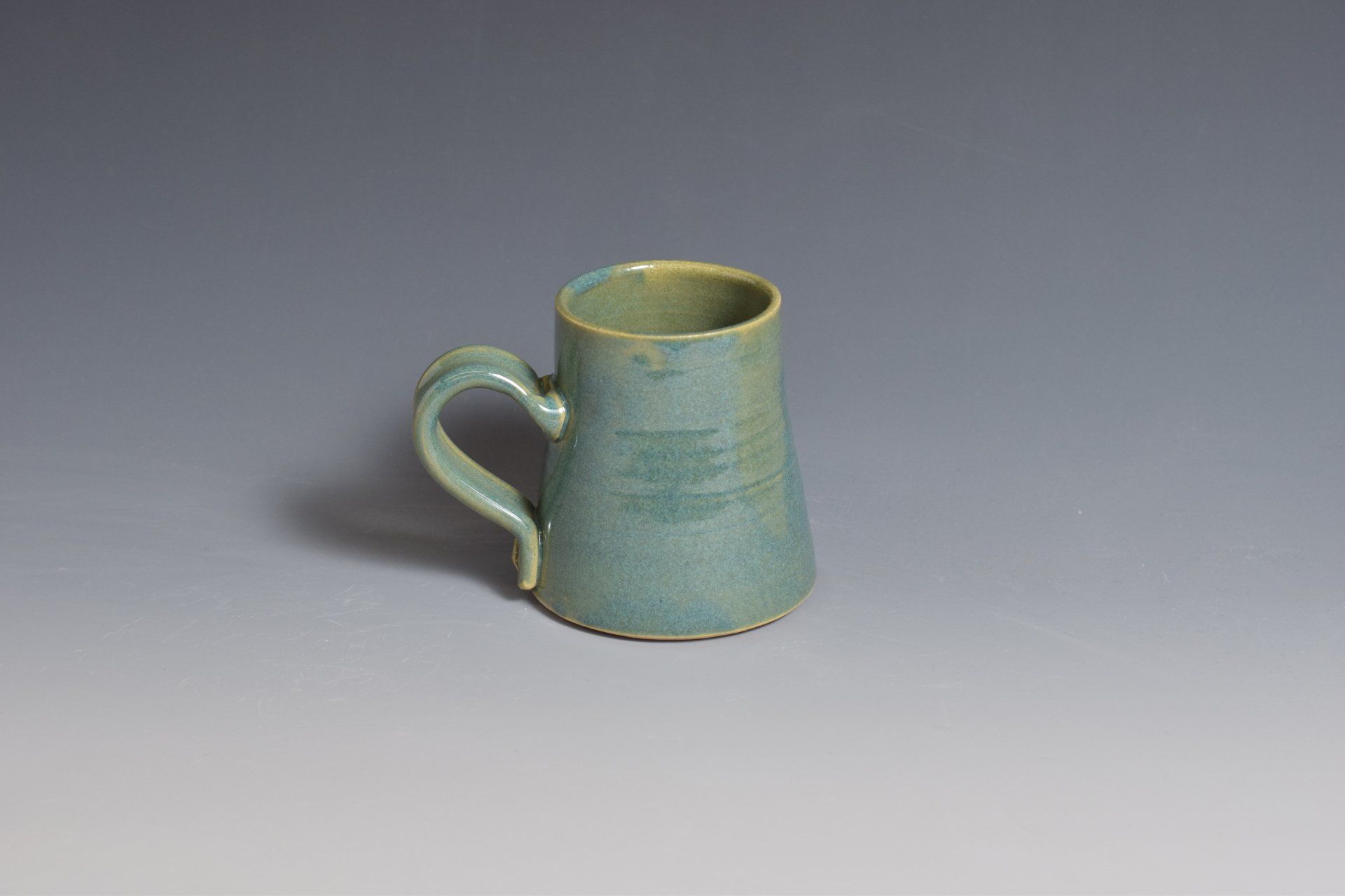 a small green mug with a handle is sitting on a table .
