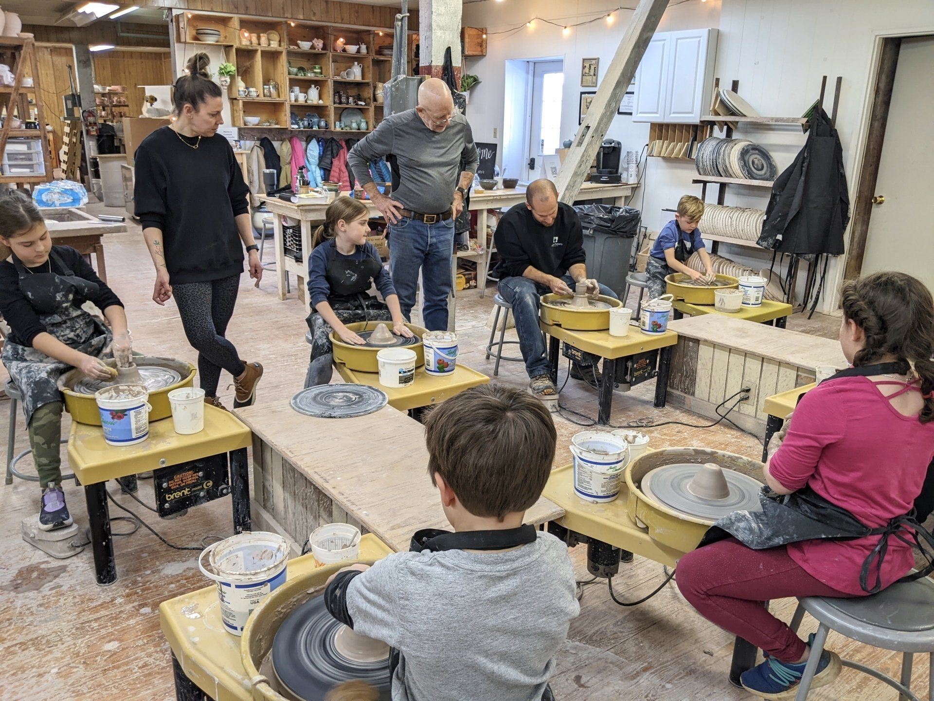 a group of people are working on pottery wheels in a pottery studio .