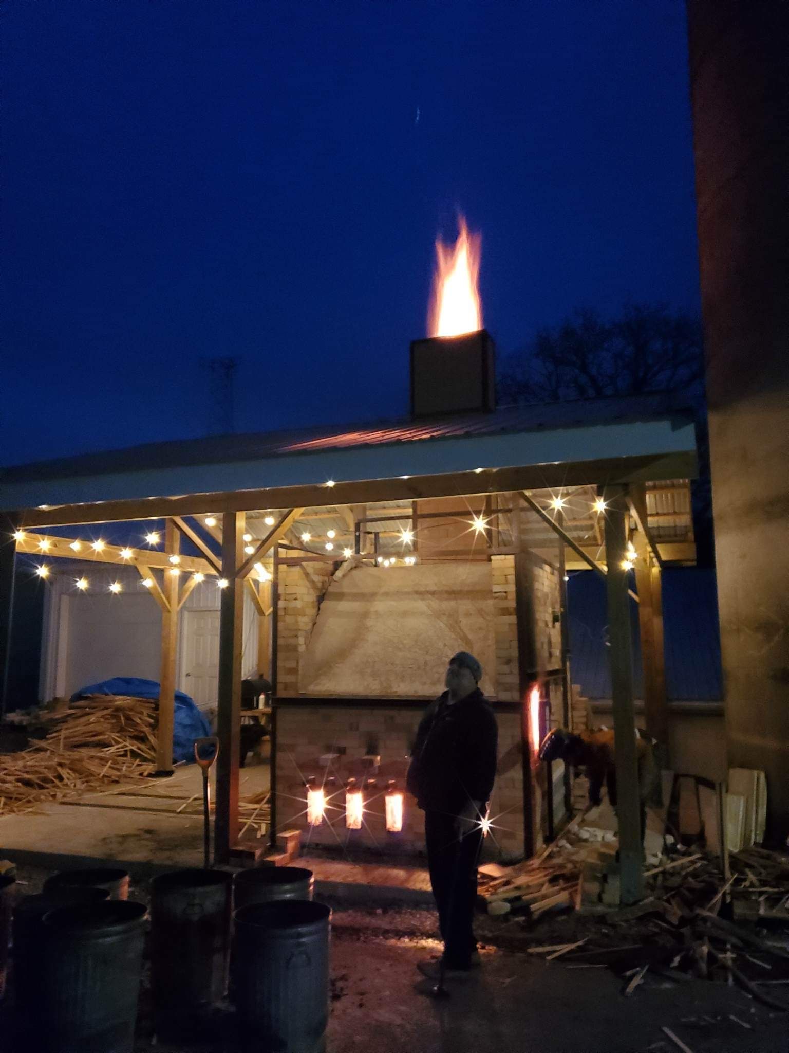 A man is standing in front of a fire at night