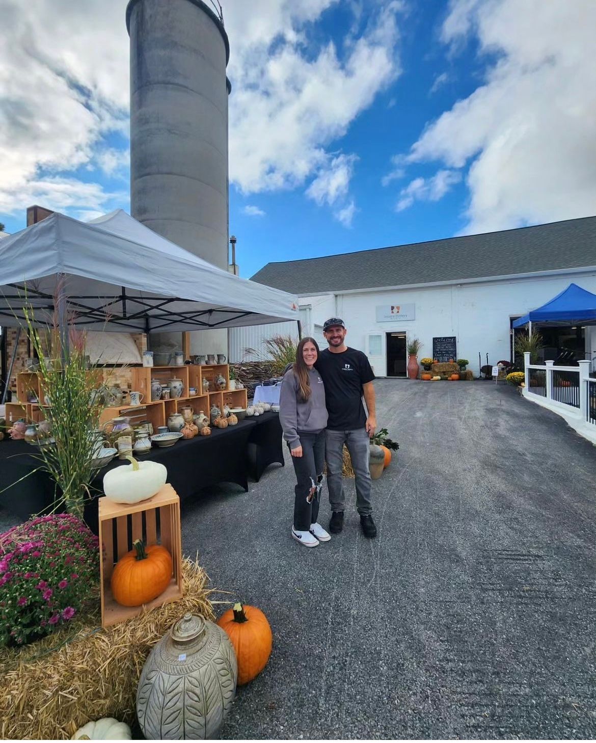 A man and a woman are posing for a picture in front of a silo.