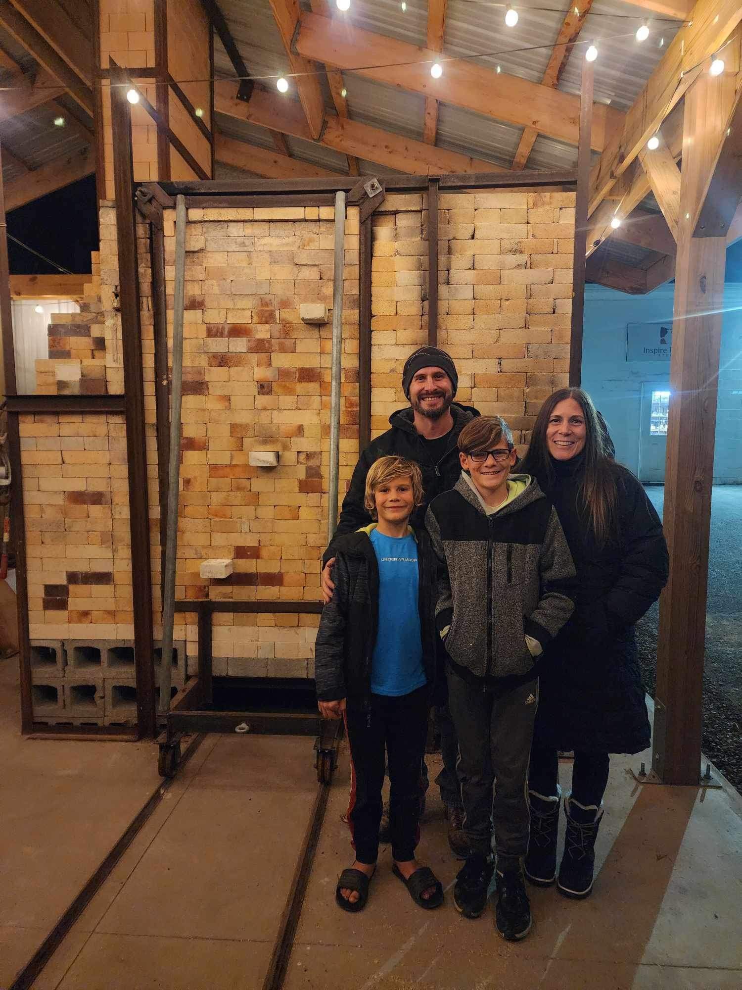 A family is posing for a picture in front of a brick wall.