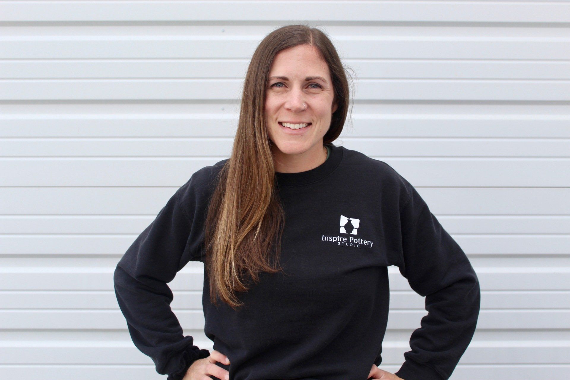 A woman wearing a black sweatshirt is standing with her hands on her hips.