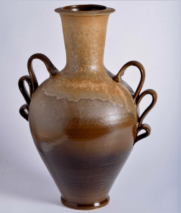A group of children are sitting at tables in a pottery studio.