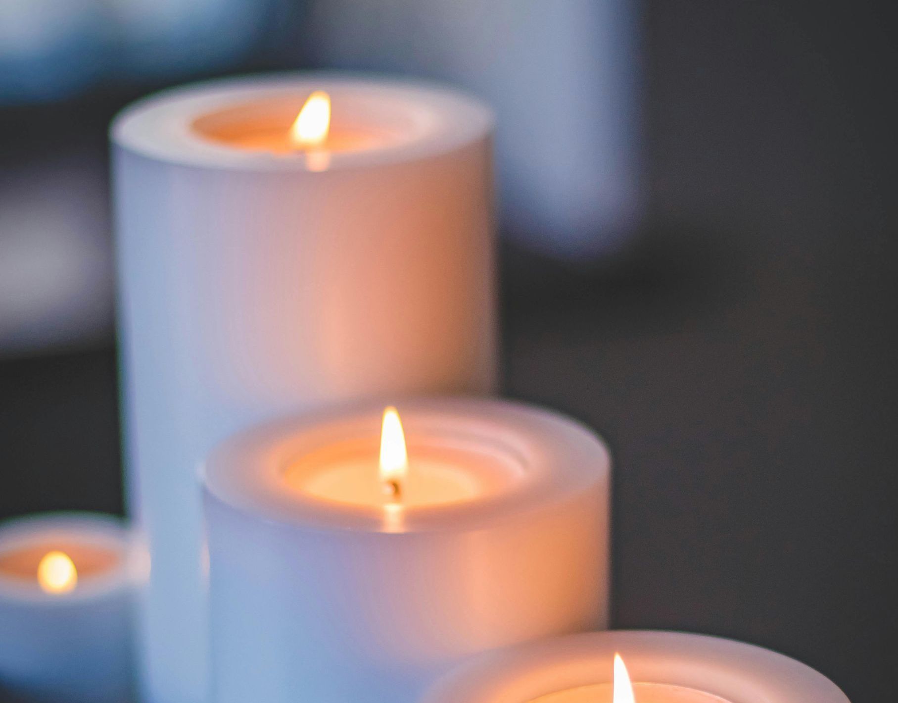 Lit white pillar candles in a dimly lit setting.