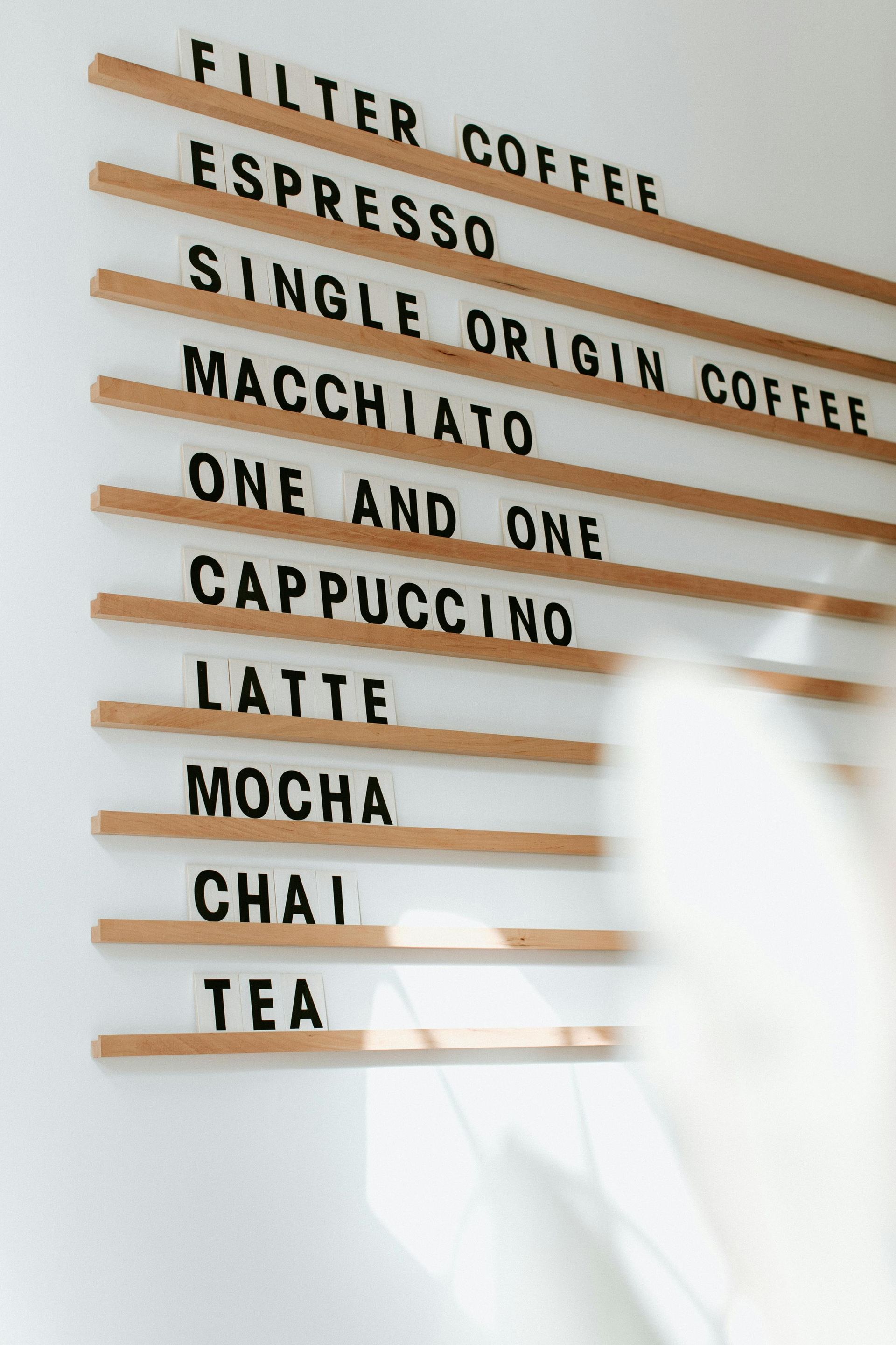 Coffee menu on a wooden board against a white wall, listing various coffee drinks.