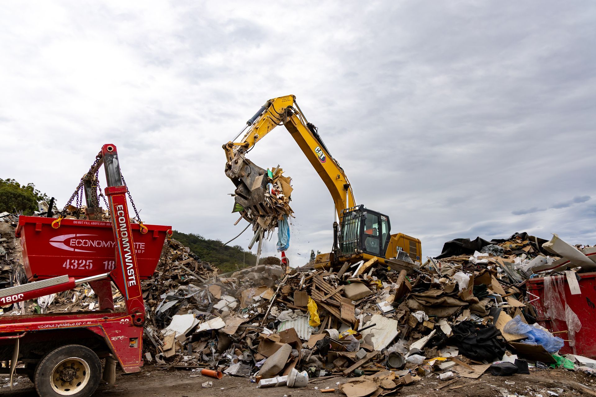 Yellow Excavator Loading Debris — Economy Waste Group | Skip Bins Central Coast In Long Jetty, NSW
