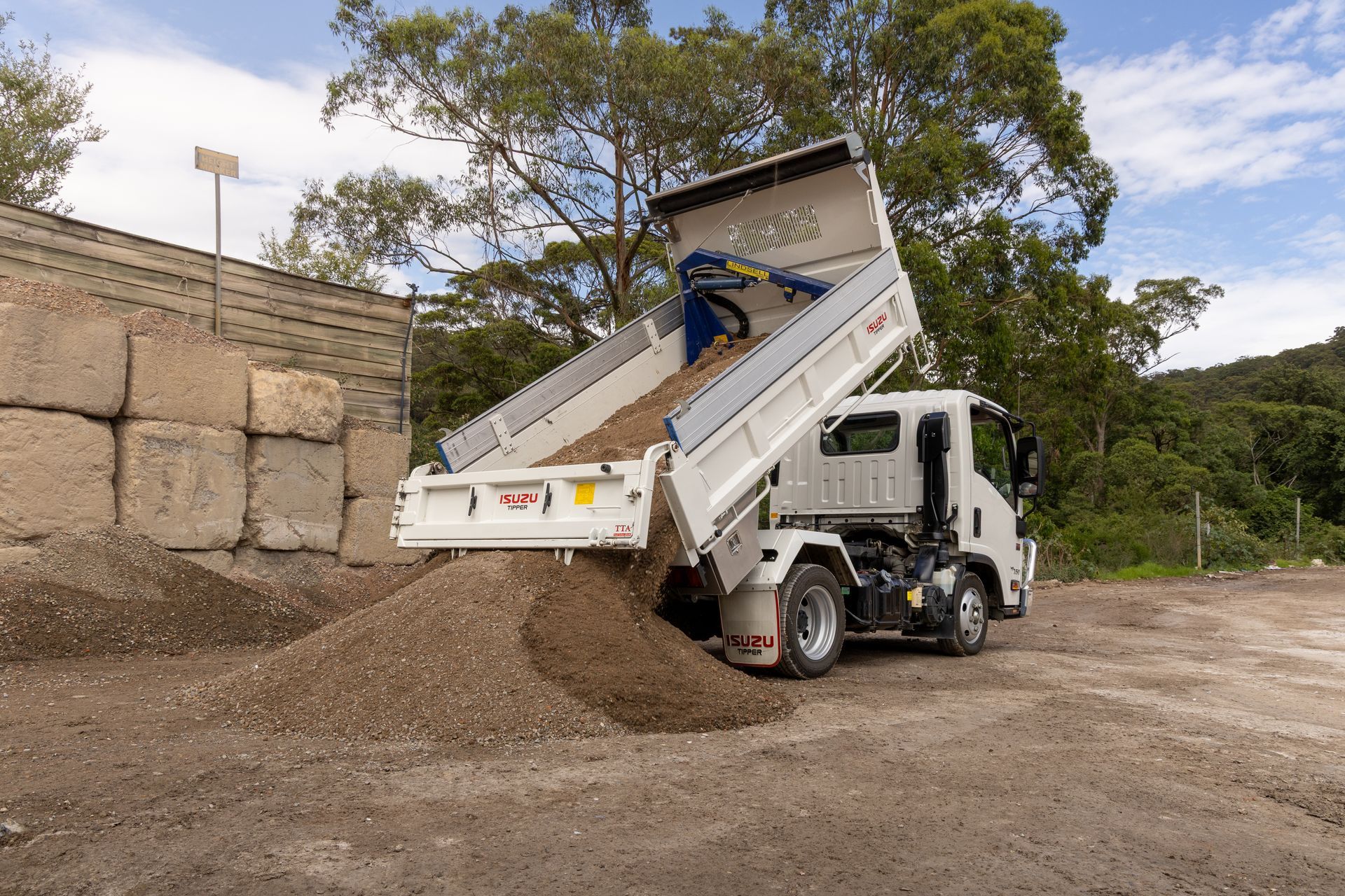 White Dump Truck Unloading Gravel at a Worksite — Economy Waste Group | Skip Bins Central Coast In Lisarow, NSW