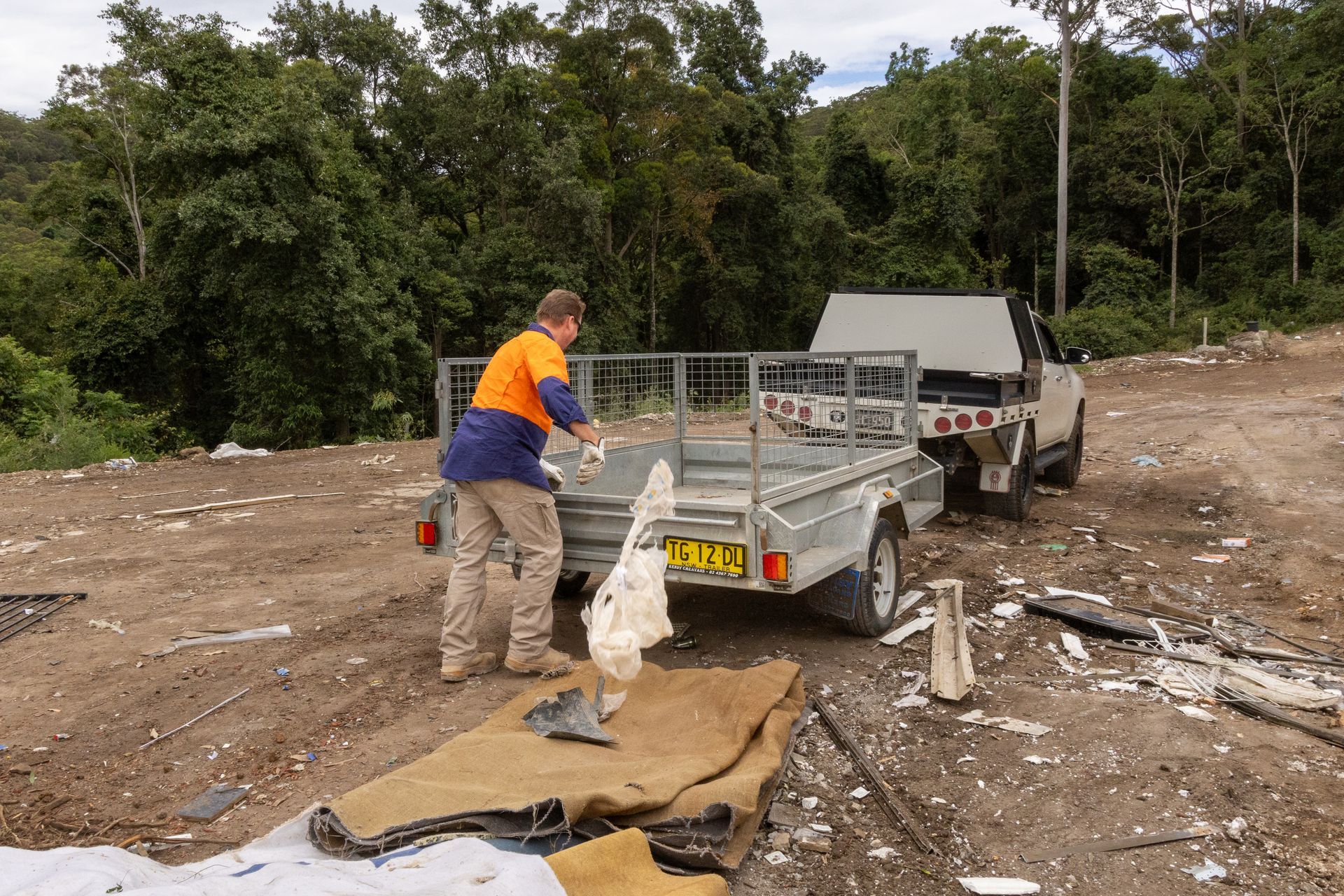 Person Loading Debris Into a Trailer — Economy Waste Group | Skip Bins Central Coast In Morisset, NSW