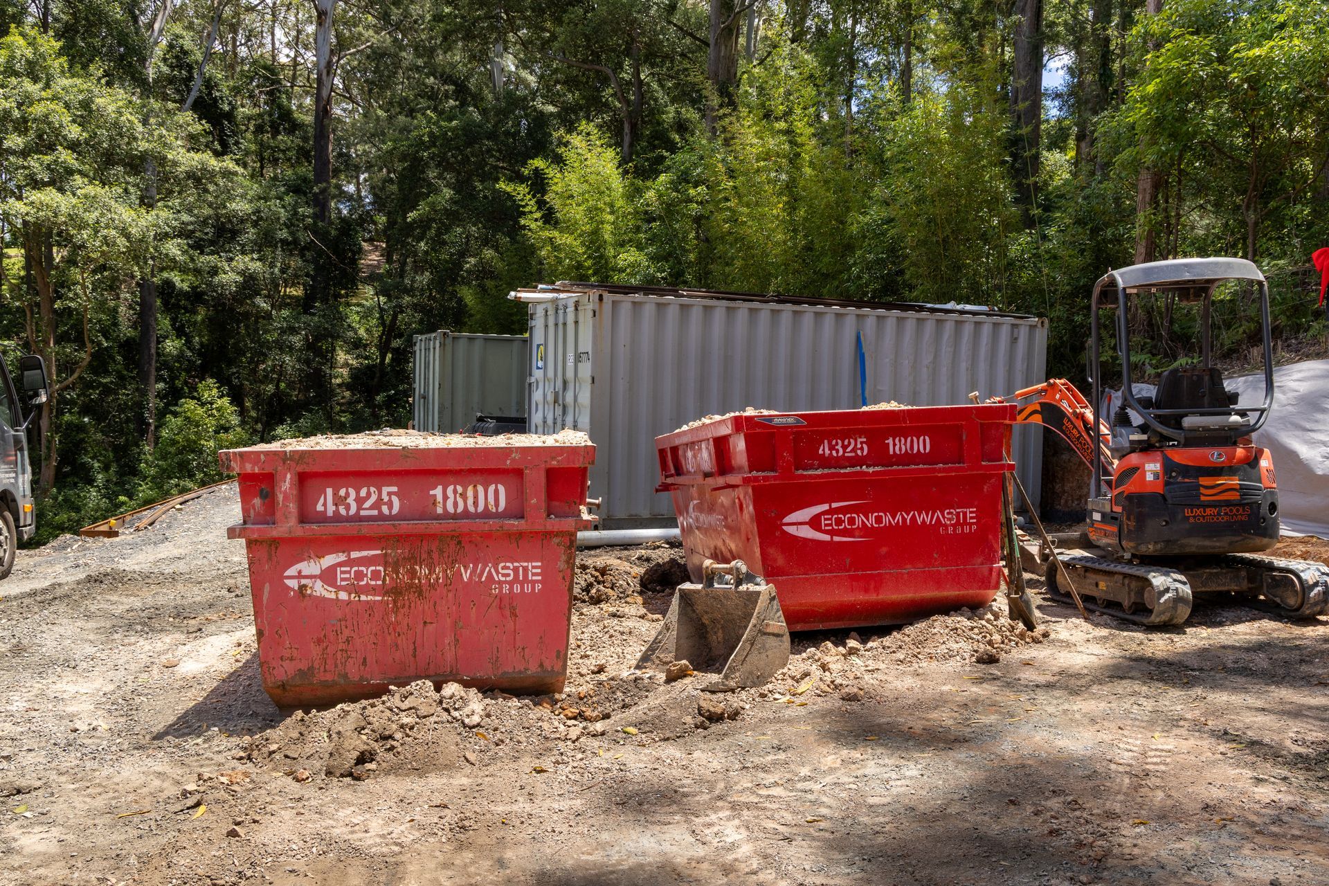 A Man And Woman Standing In Front Of A Red Dumpster — Economy Waste Group | Skip Bins Central Coast In West Gosford, NSW