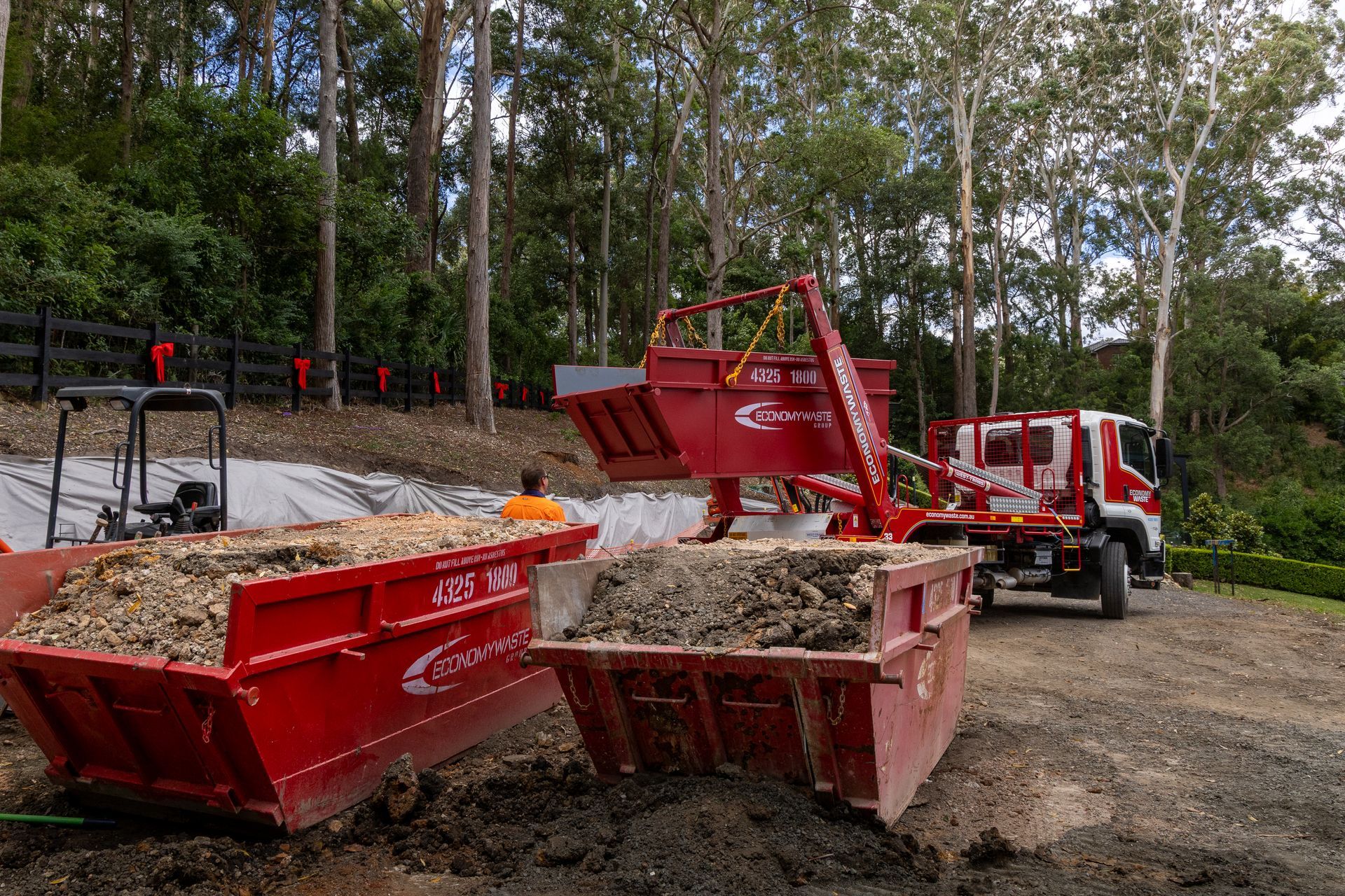 A Dump Truck Is Driving Down A Road — Economy Waste Group | Skip Bins Central Coast In West Gosford, NSW