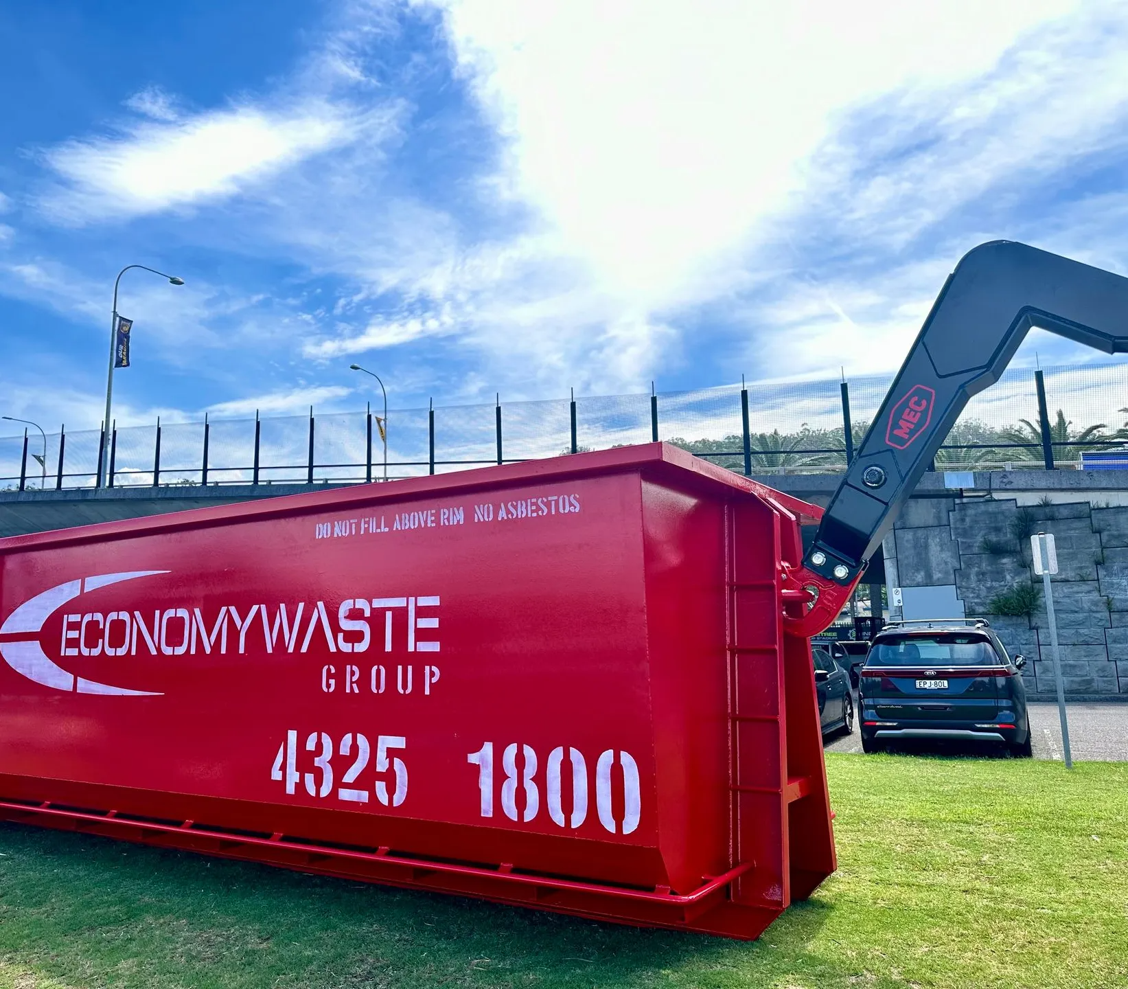 A Red Economy Waste Dumpster With a Lifting Arm — Economy Waste Group | Skip Bins Central Coast In Tuggerah, NSW