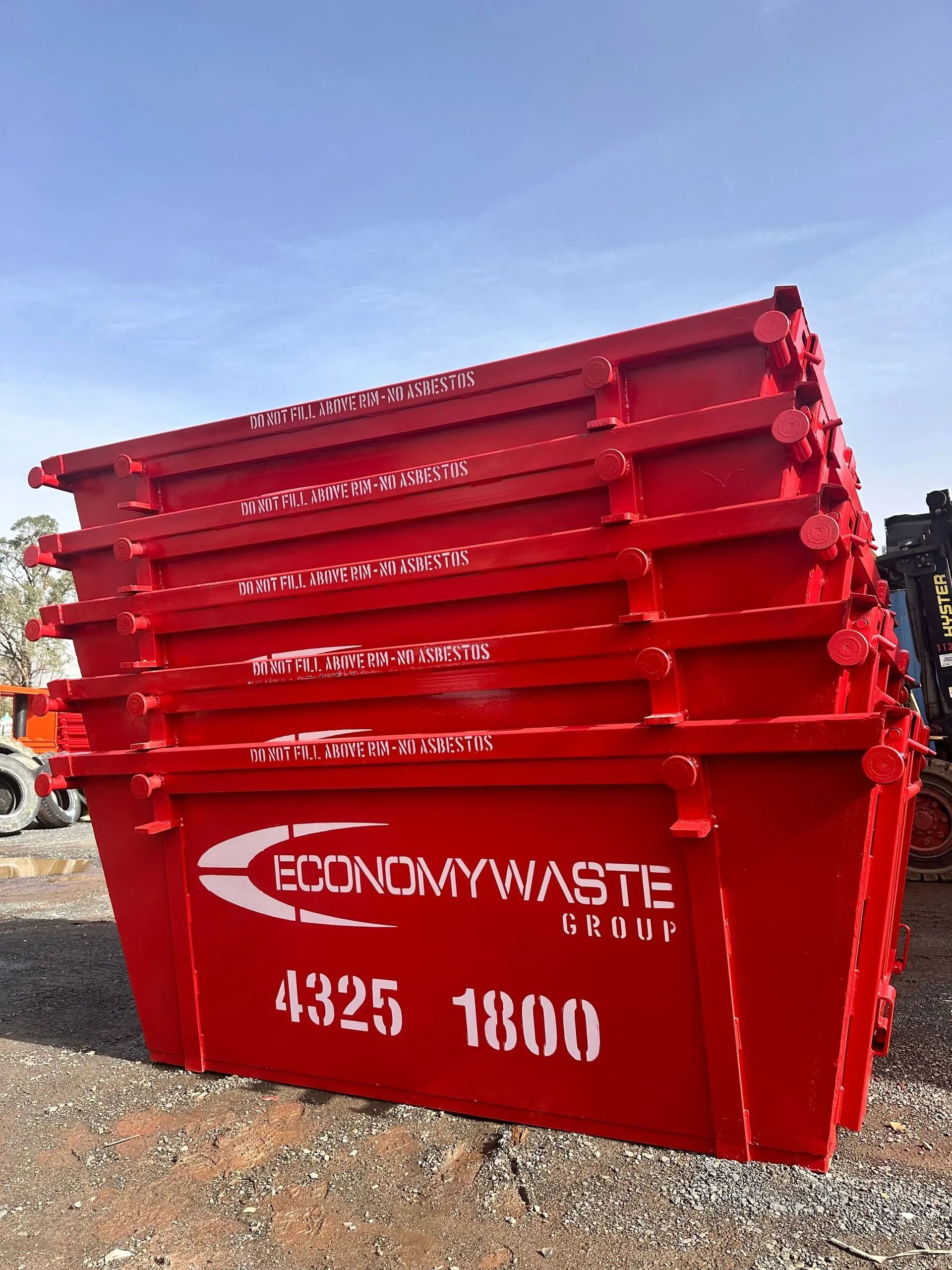 A Red Economy Waste Dumpsters Stacked Outside — Economy Waste Group | Skip Bins Central Coast In Erina, NSW