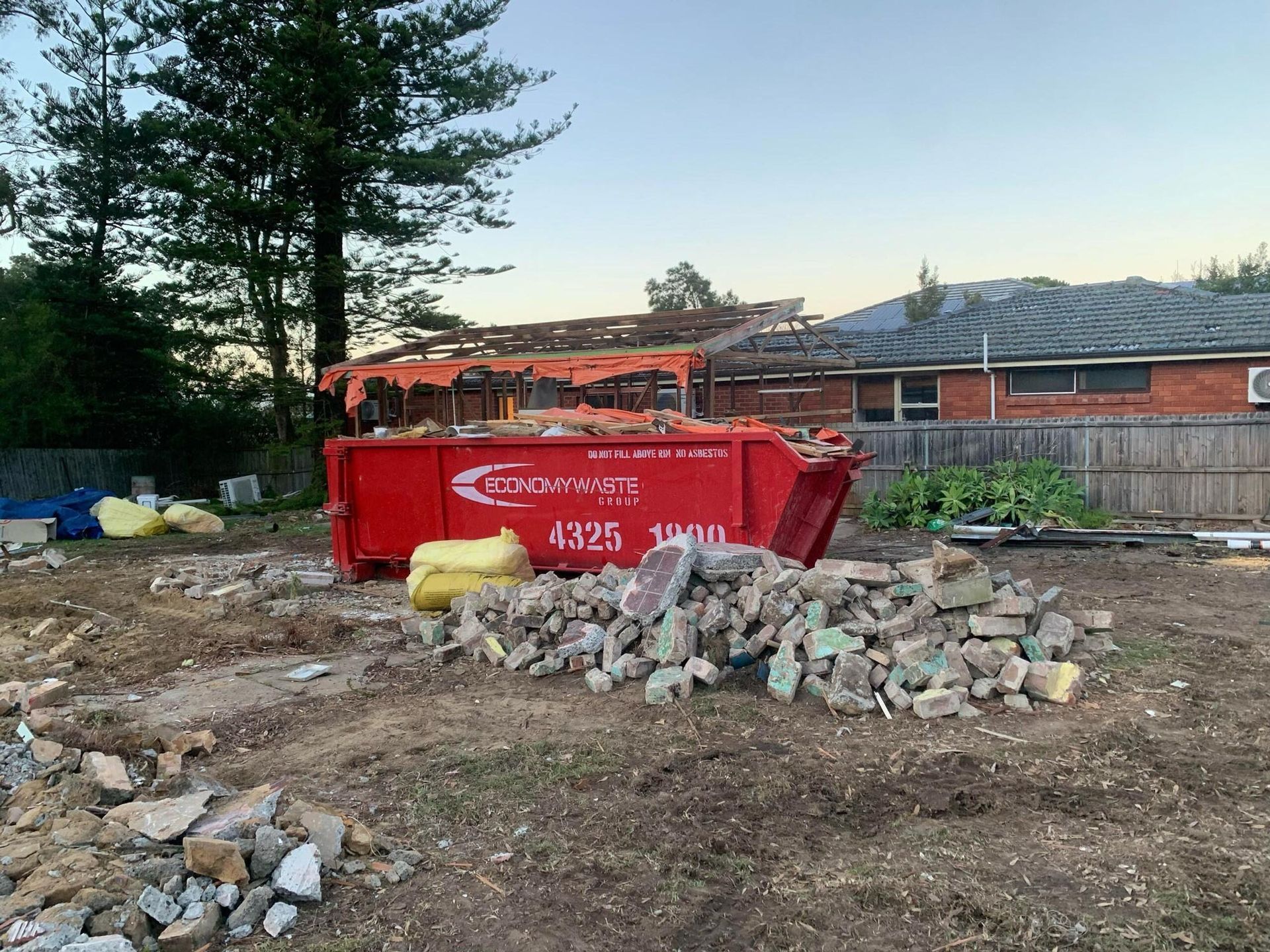 Red Dumpster Filled With Debris — Economy Waste Group | Skip Bins Central Coast In West Gosford, NSW